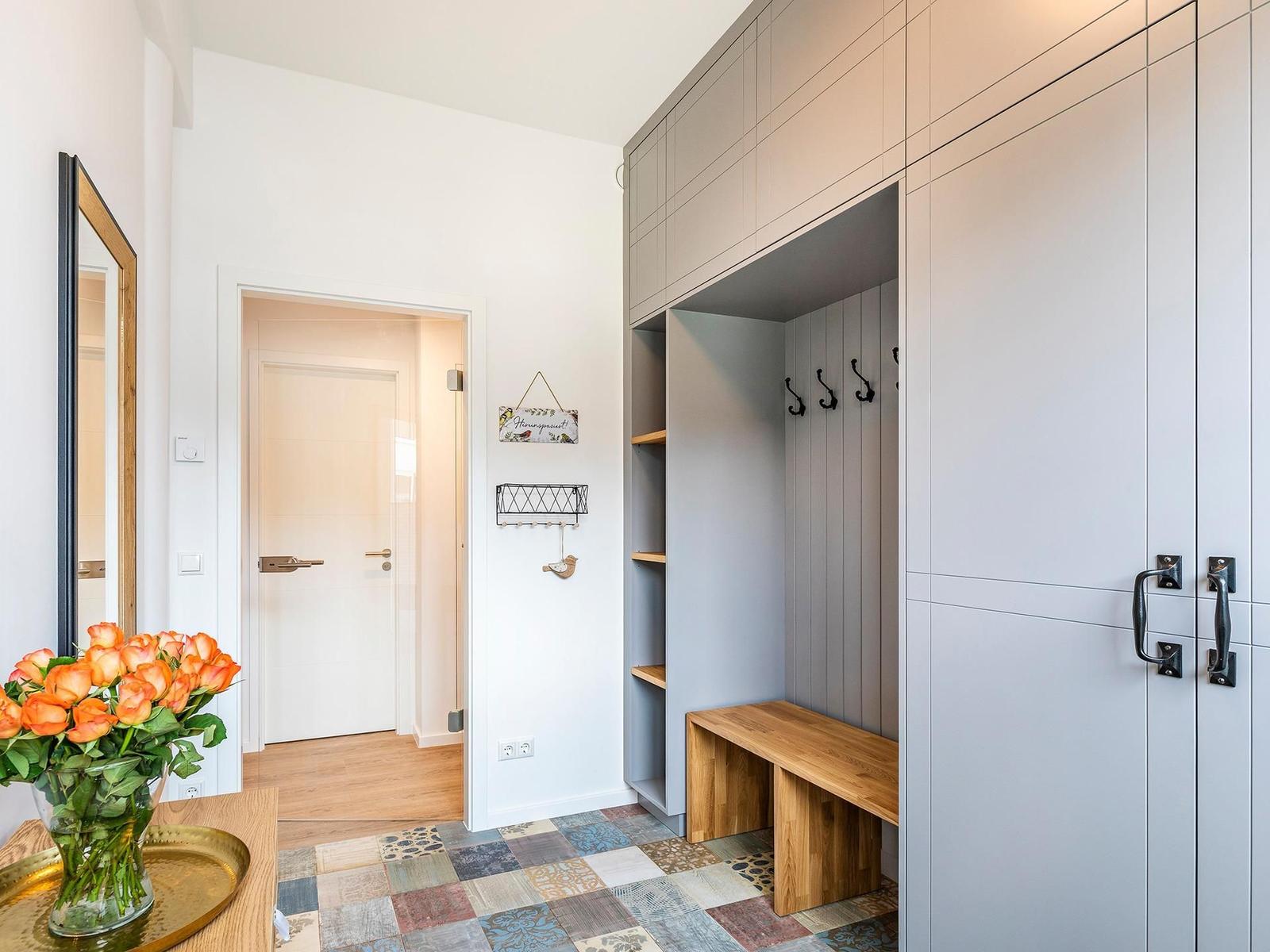 Eingangsbereich mit Garderobe, Bänkchen und Blumen auf Tisch.