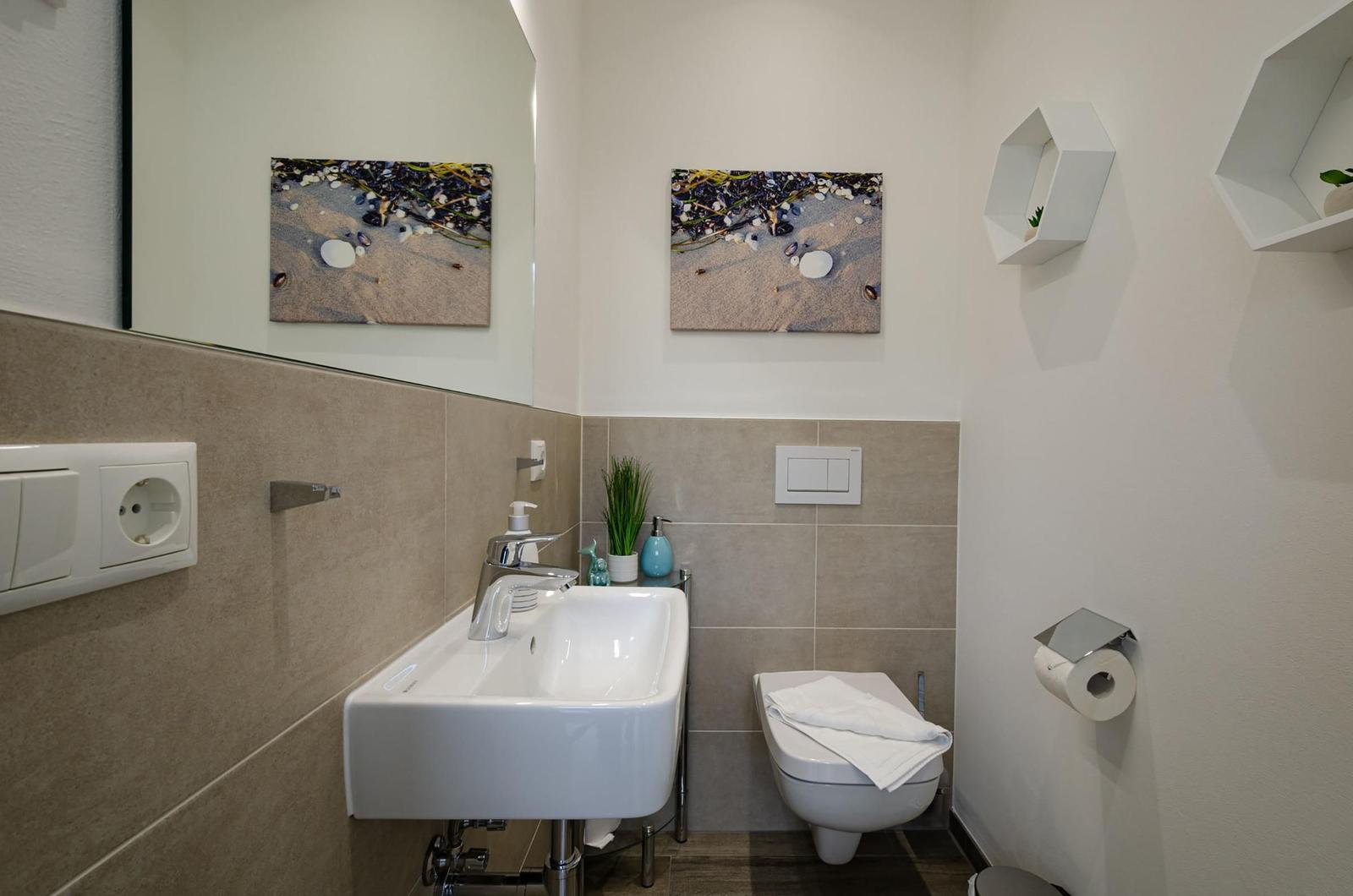 Badezimmer mit Waschbecken, Toilette und Wandbildern.