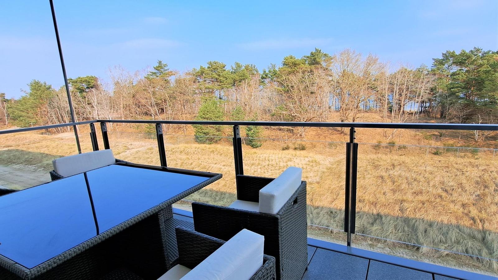 Terrace with seating area and view of forest and meadow.