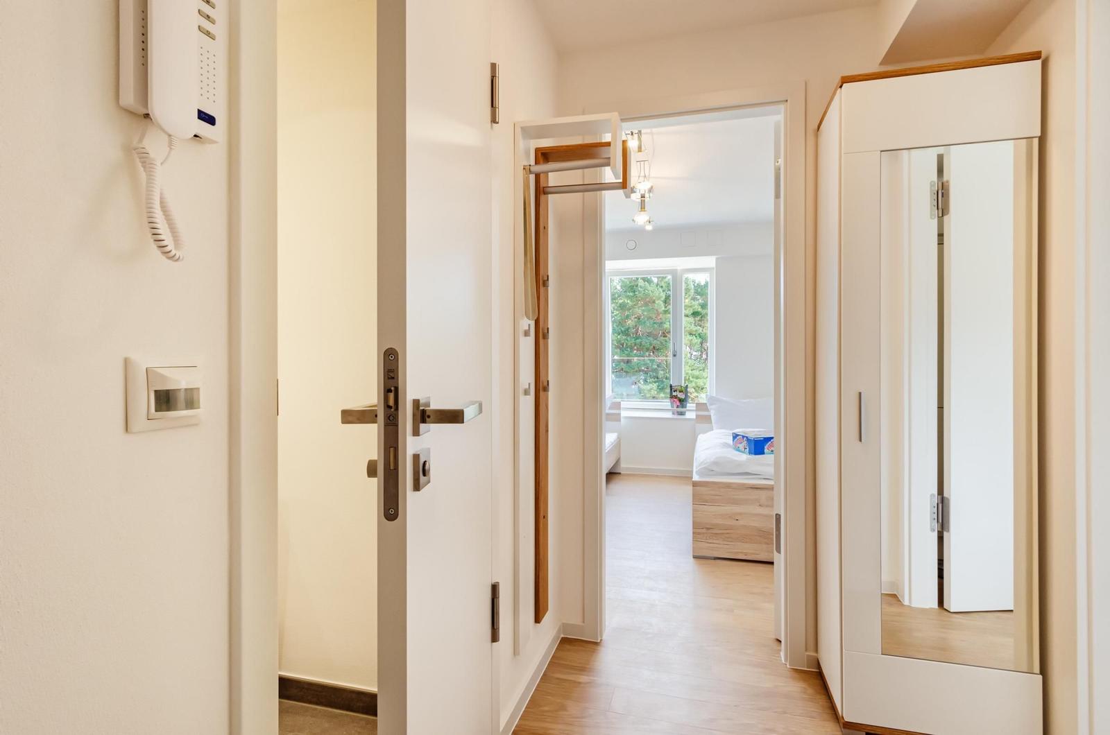 Flur mit Tür, Spiegel und Blick in Schlafzimmer mit Fenster.