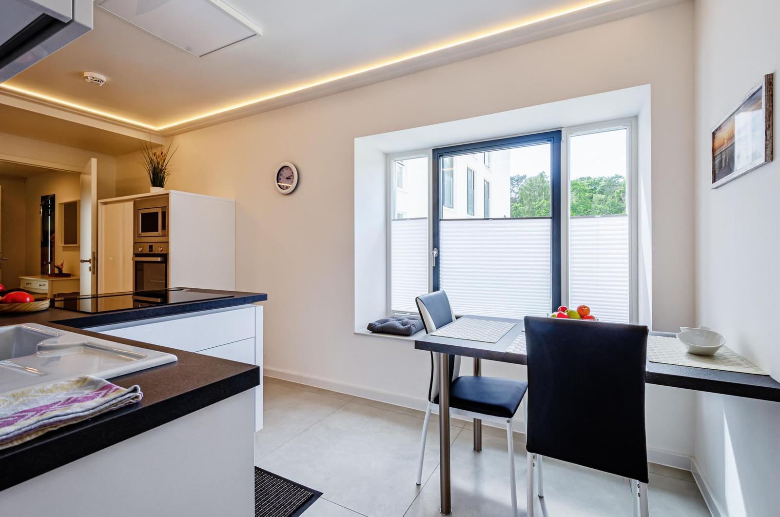 Küche mit Essbereich, Fenster mit Jalousie und schwarze Sitzbank.