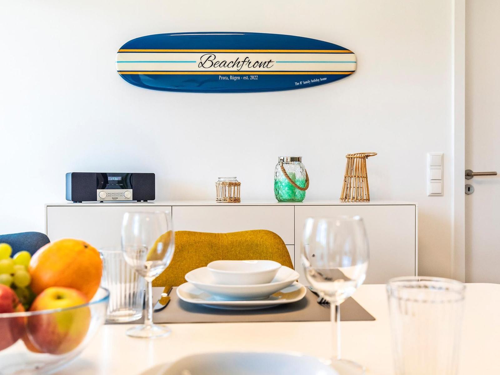 Esszimmer mit Tisch, Stühlen und Dekoration. Wanddekoration mit Surfboard-Design.