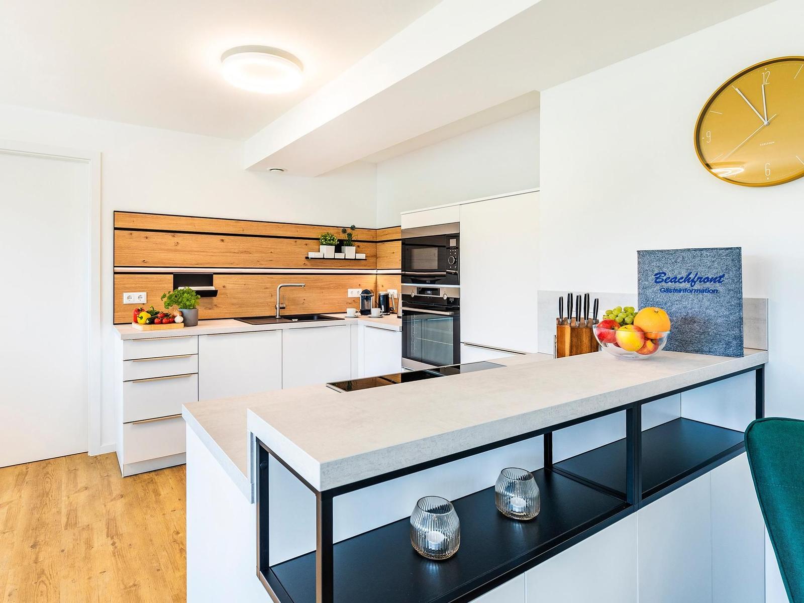 Moderne Küche mit Holzwand, Edelstahlgeräten und Kücheninsel mit Obst.