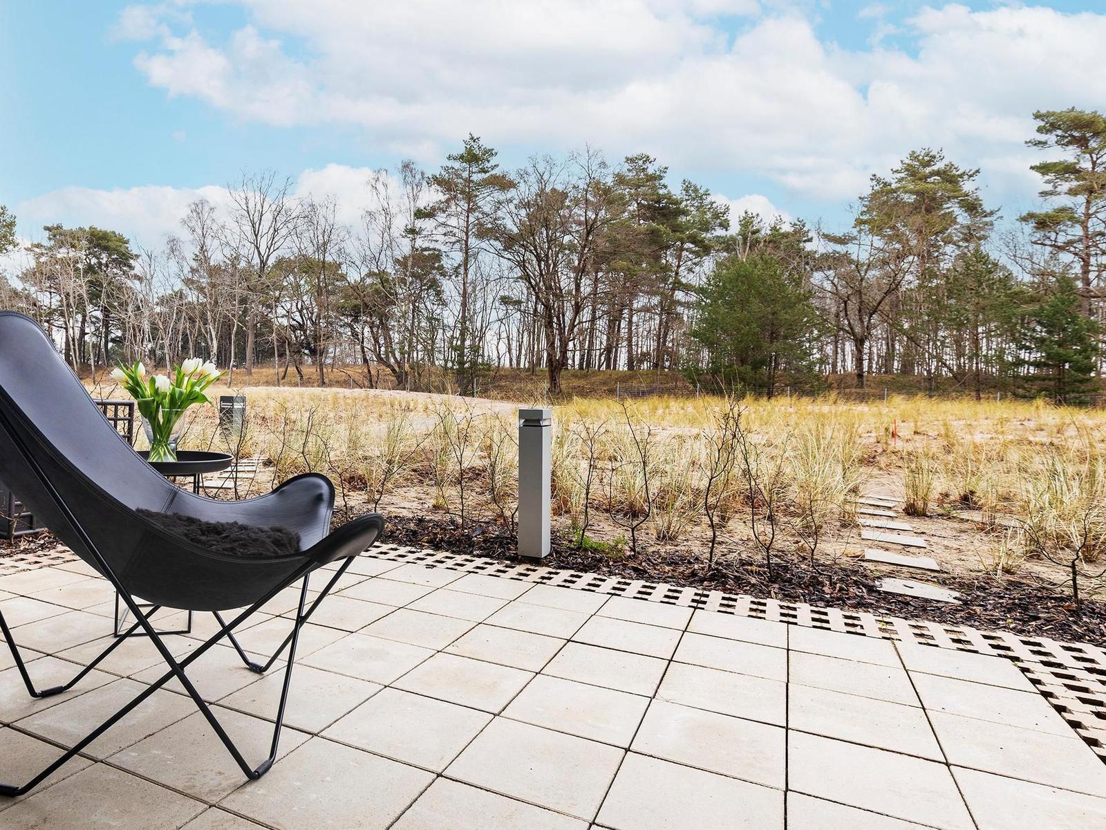 Terrasse mit schwarzer Lounge-Sitzgelegenheit und Blick auf Wald.