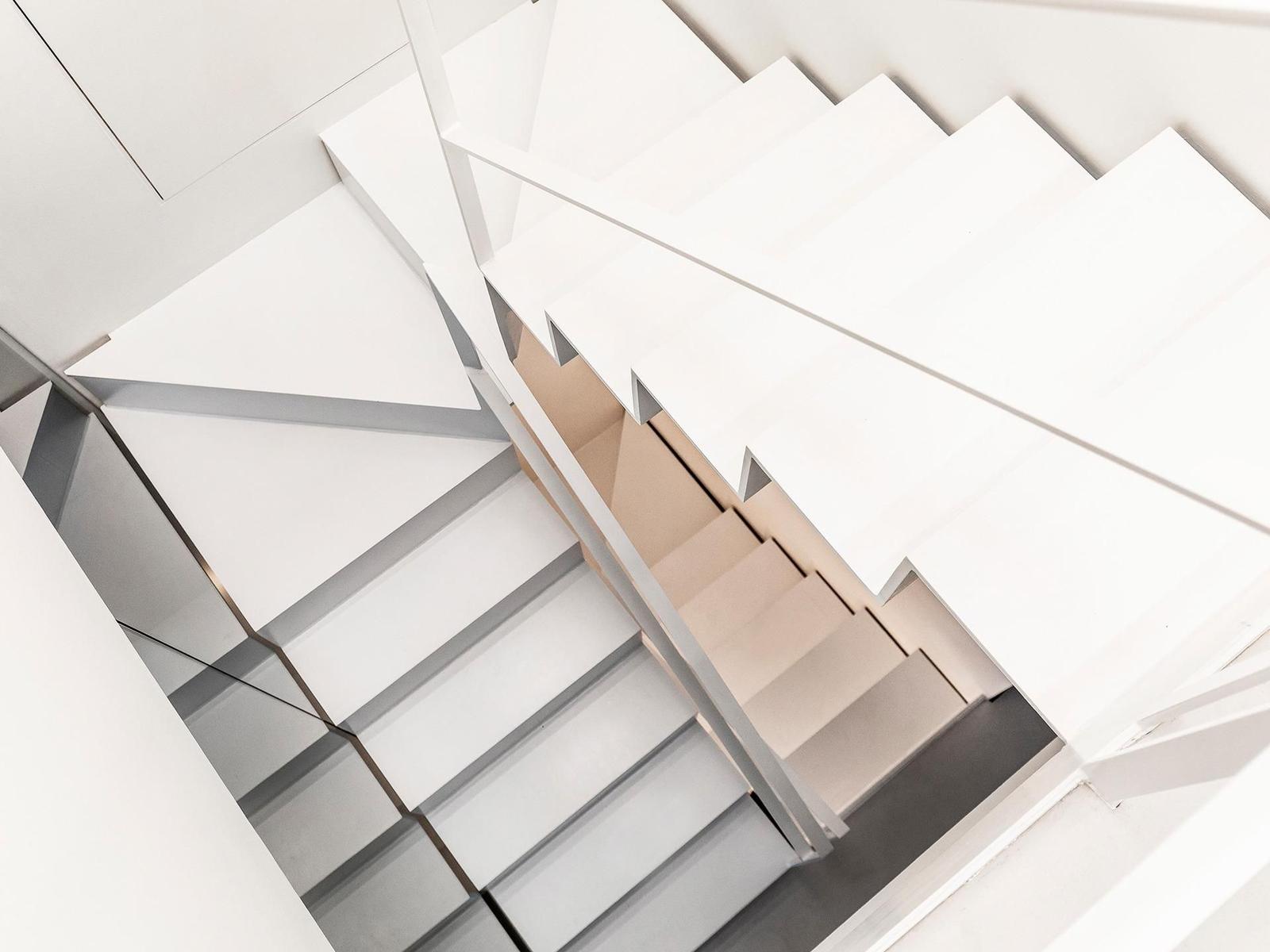 Moderne Treppe mit weißen Stufen und metallischen Geländern in minimalistischem Design.