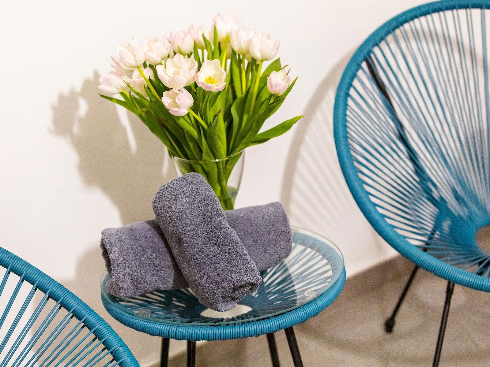Blauer Stuhl und Tisch mit Tulpen und Handtüchern.