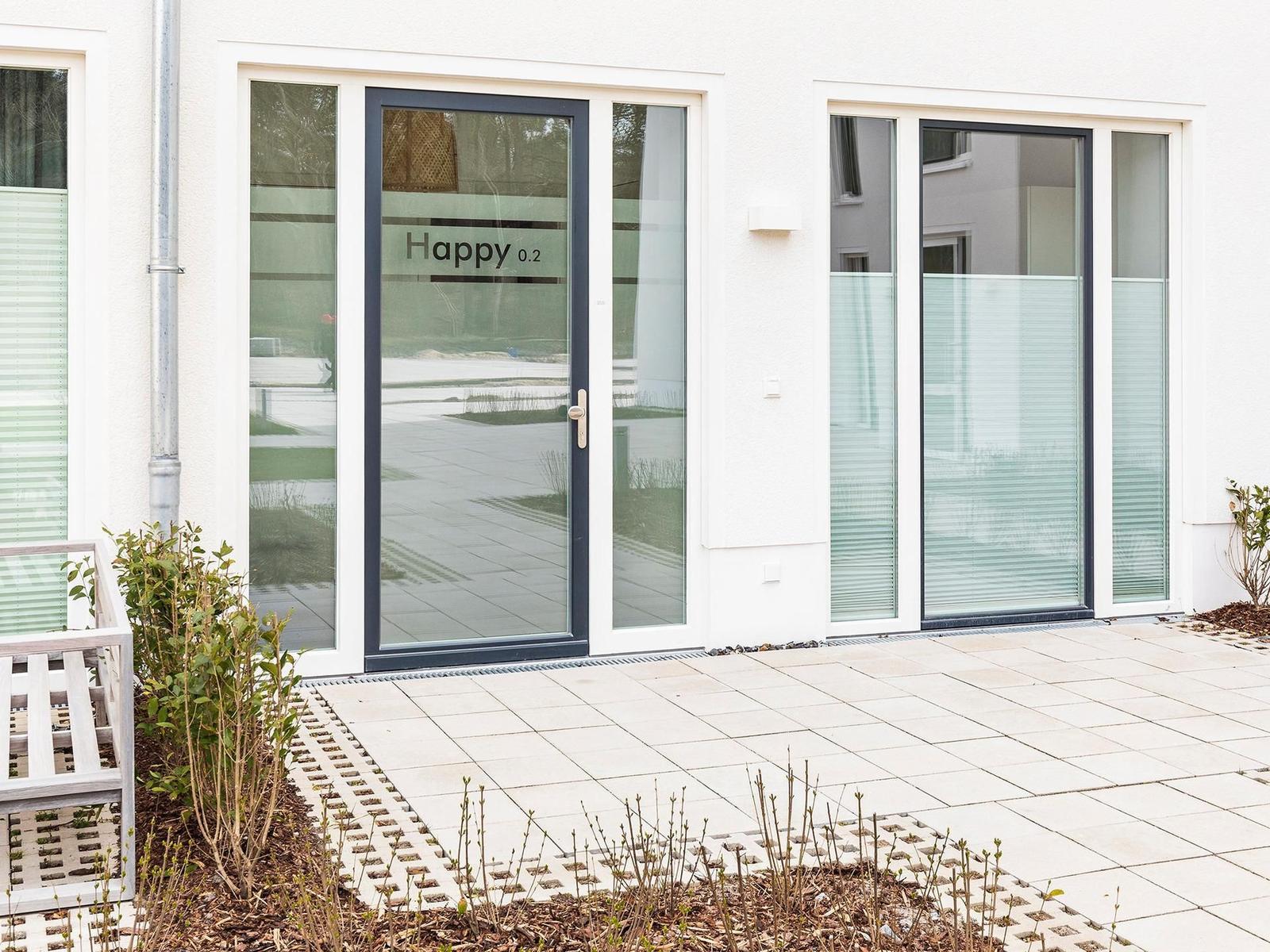 Haus mit Glasfront und Eingangstür mit Aufschrift Happy 0.2