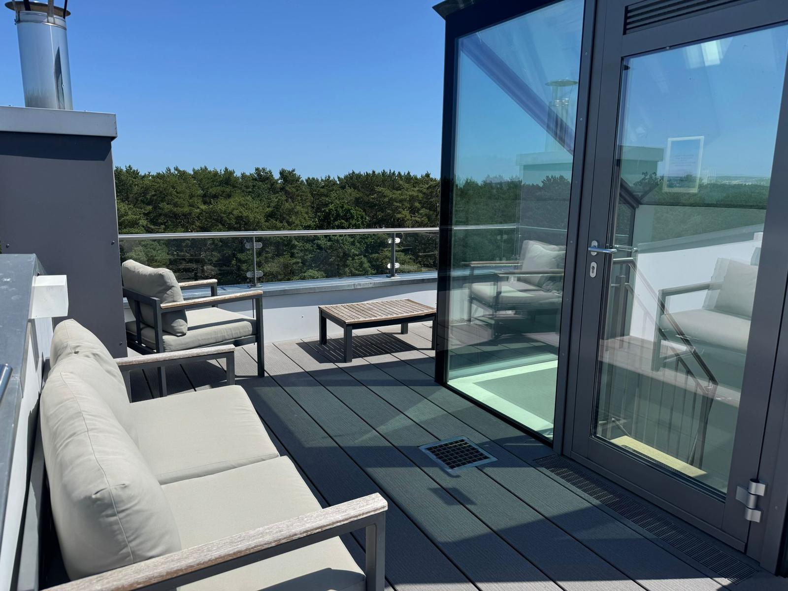 Terrasse mit Sitzgelegenheiten und Blick auf einen Wald.