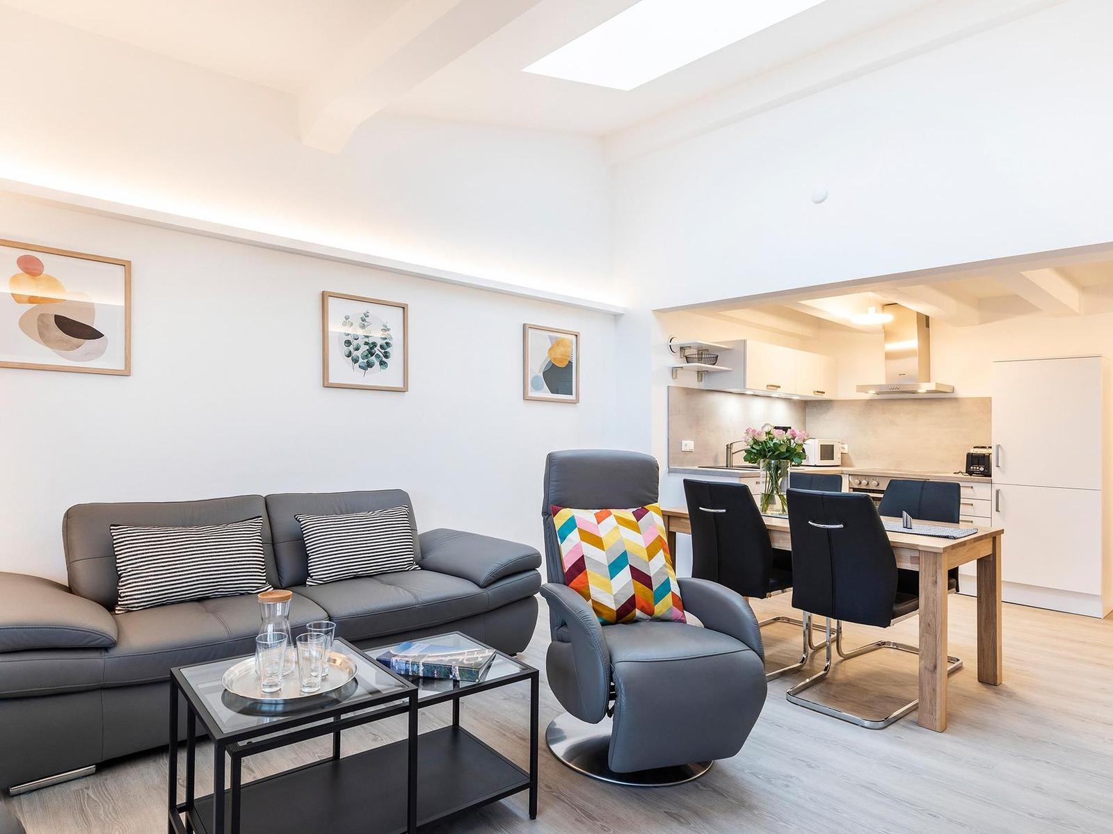 Wohn/Essbereich: Sofa, Sitzbereich, Essbereich, smartTV, Zugang zum Balkon mit Insektenschutztür, hoher Raum mit Dachfen