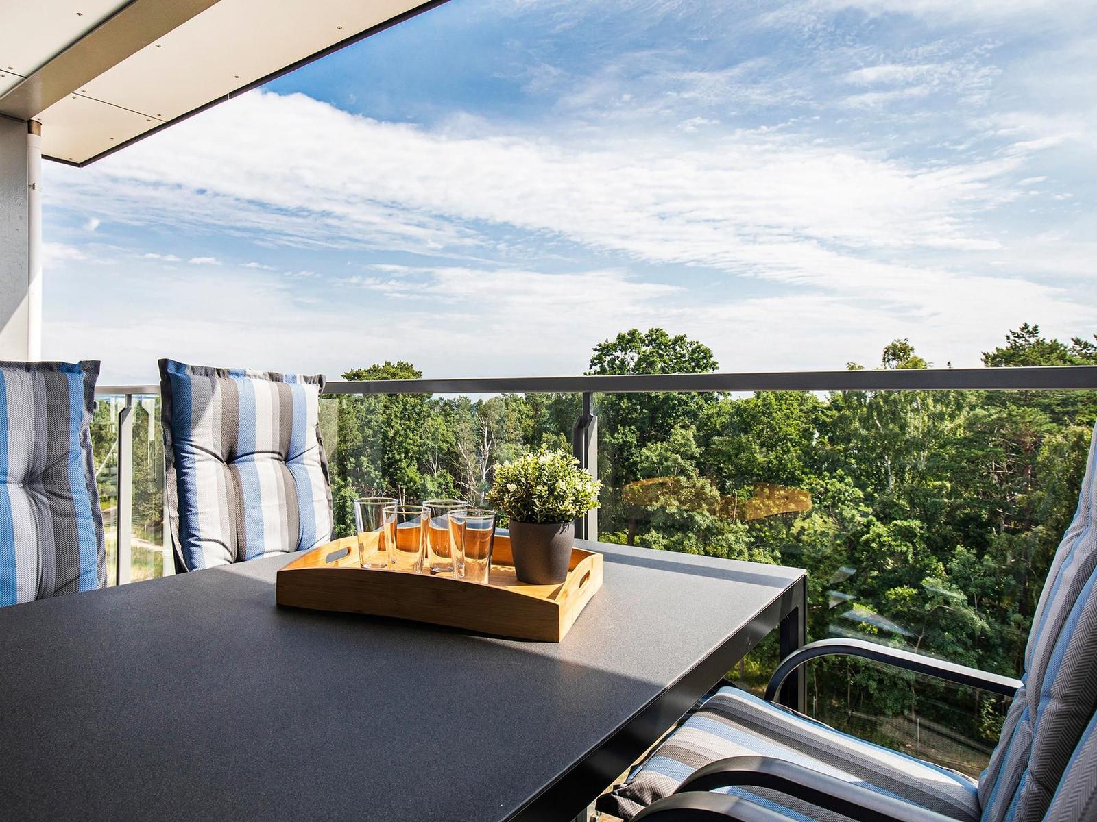 Terrasse mit Tisch, Stühlen und Blick auf Wald.