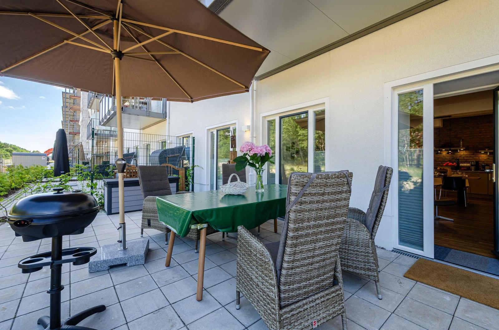 Terrace with table, chairs, umbrella, and grill. Entrance to the kitchen.