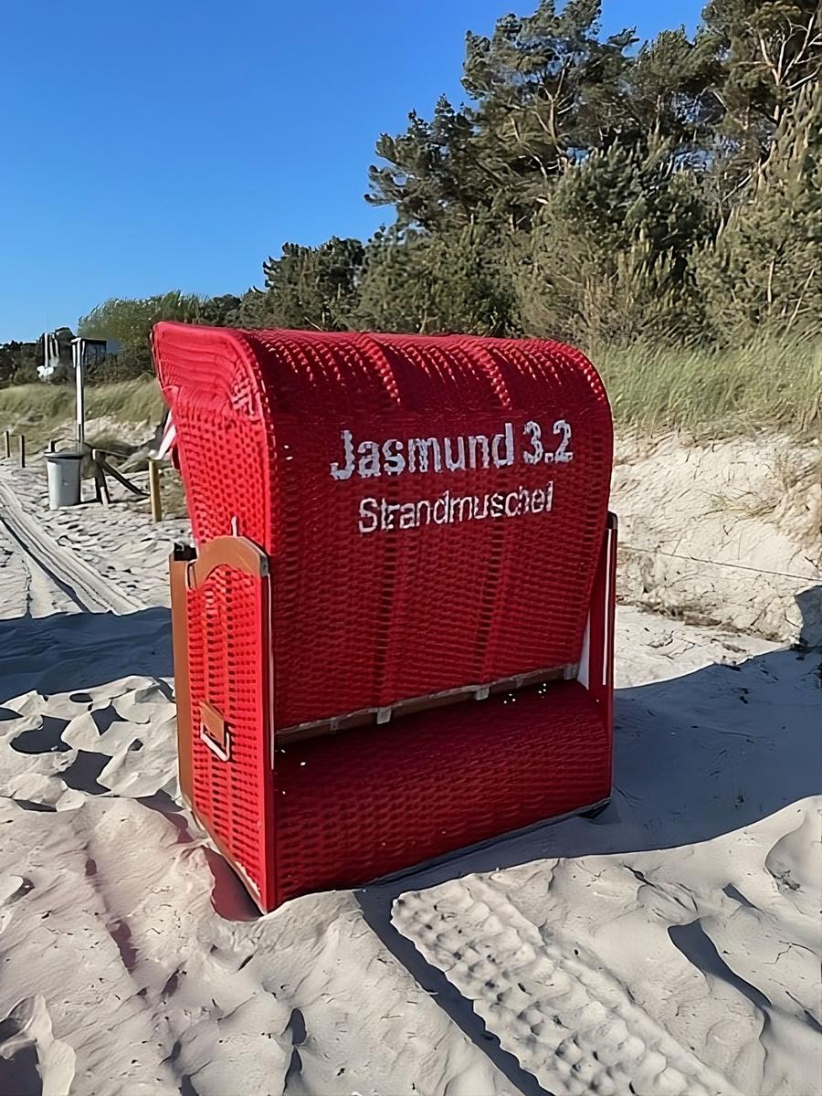 Roter Strandkorb mit Aufschrift Jasmund 3.2 Strandmuschel auf Sandstrand