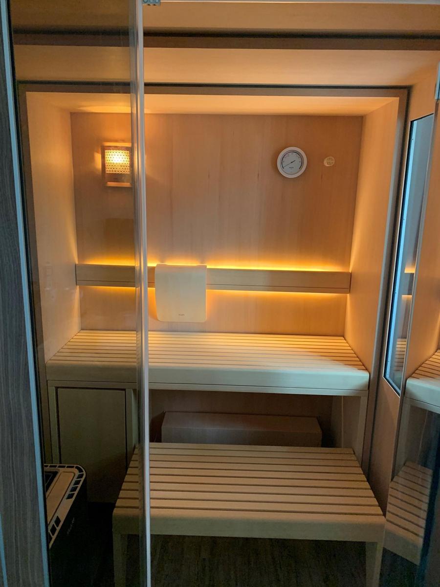 Sauna with wooden bench, thermometer, and warm lighting.