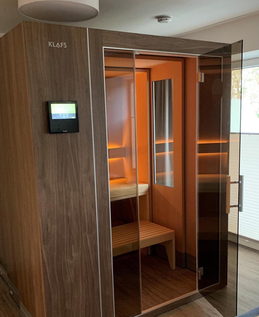Sauna with glass door and digital control. Wooden interior with bench and lighting.
