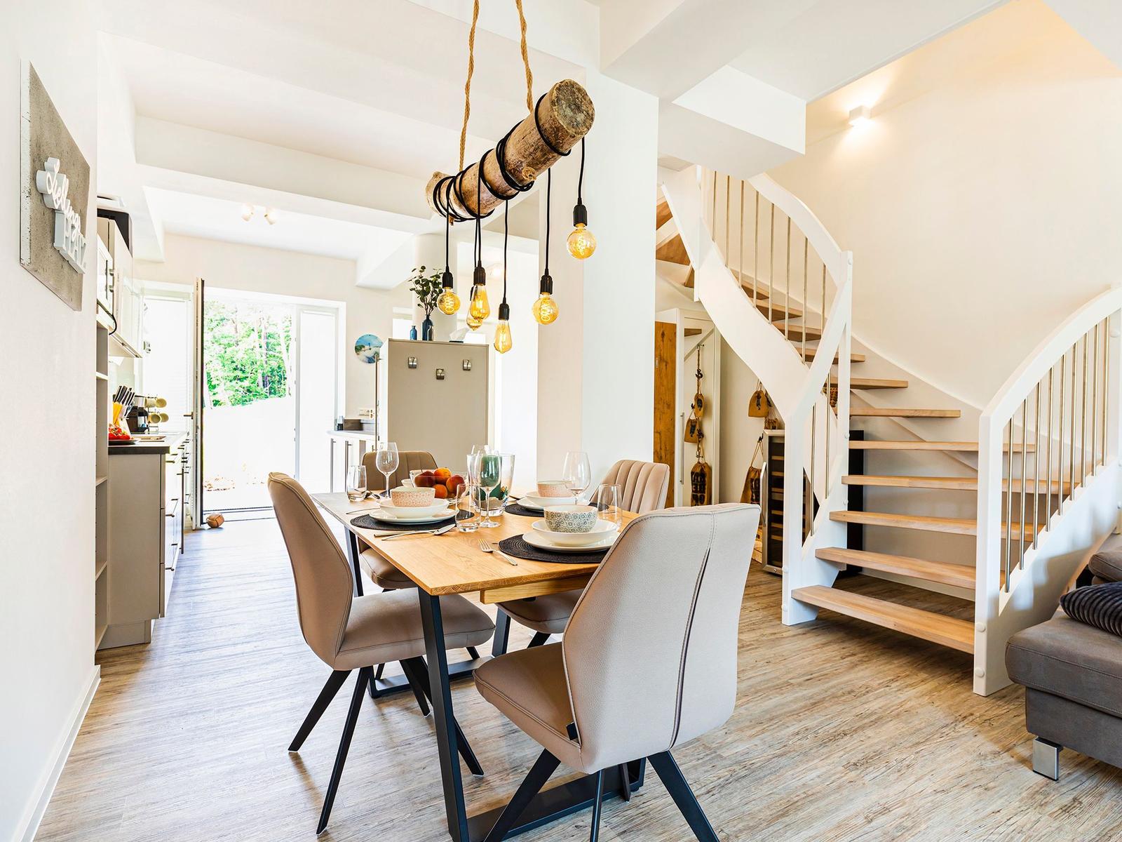 Dining room with table, chairs, and spiral staircase. Ceiling light with wooden pipe and bulbs.