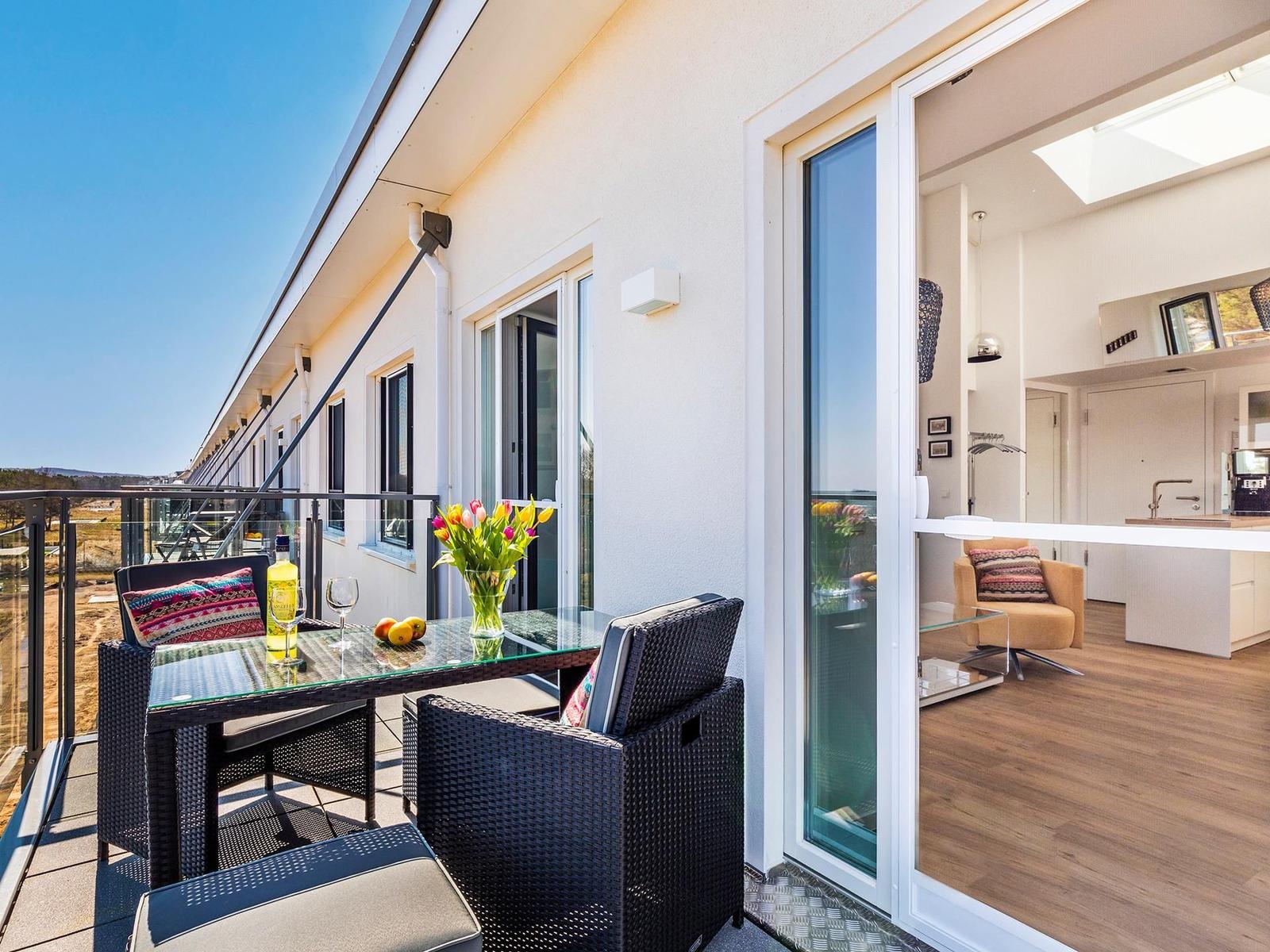 Terrasse mit Sitzgruppe und Blick auf die Landschaft. Durchgehende Glasfront zum Innenraum.