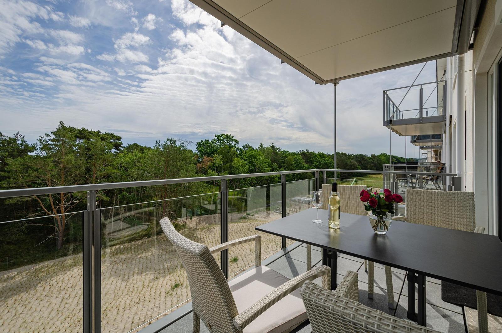 Terrasse mit Tisch, Stühlen und Blick auf Wald.