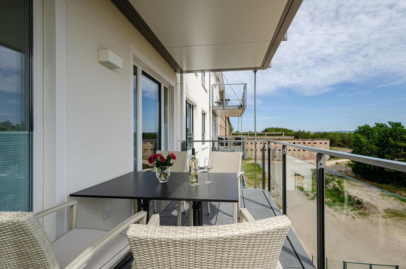 Terrasse mit Tisch, Stühlen und Blumen. Blick auf Gebäude und Bäume.