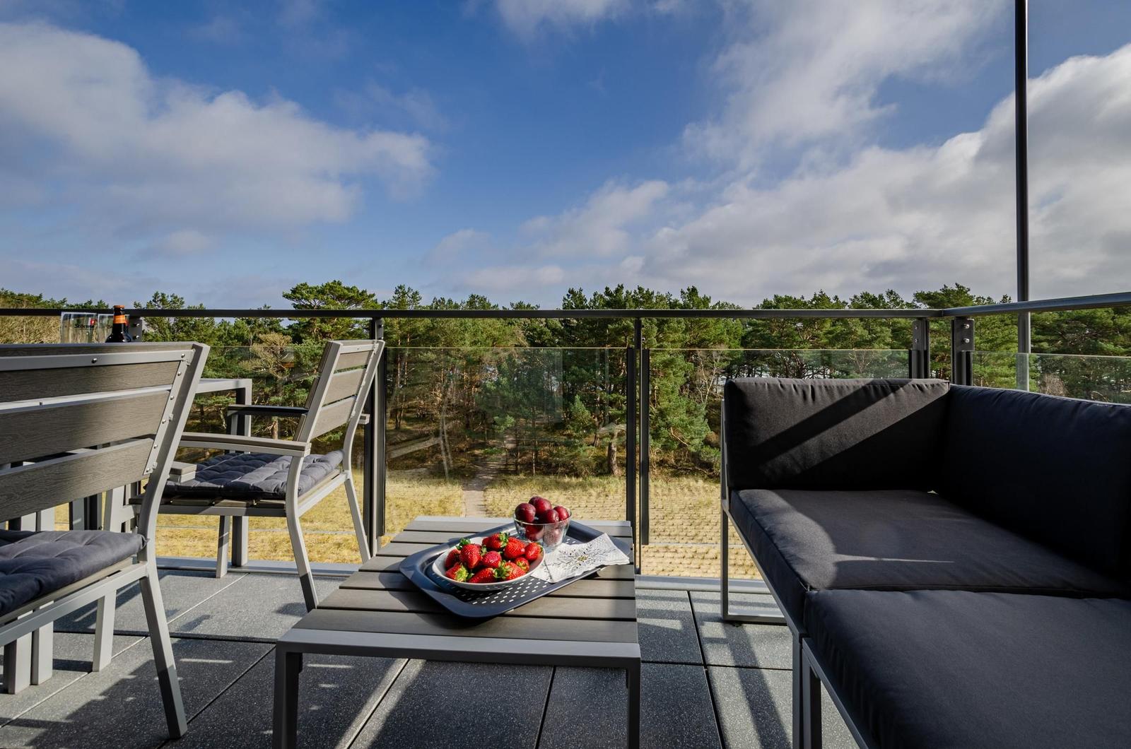 Terrasse mit Sitzgruppe und Obstteller, Blick auf Wald und Himmel.