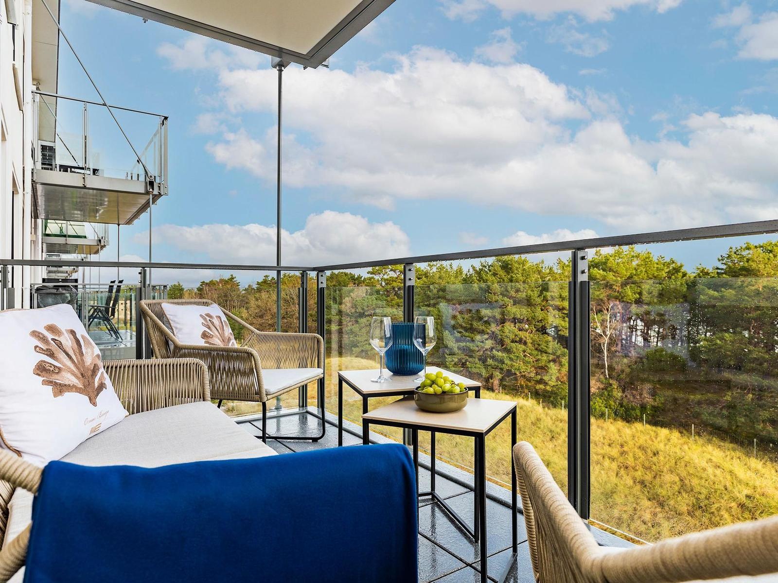 Terrasse mit Sitzgelegenheiten und Blick auf Wald und Himmel.