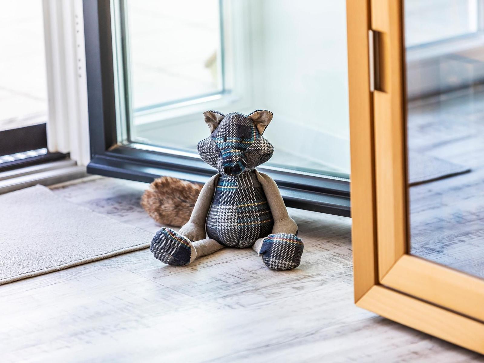 Ein Plüschfuchs sitzt vor einer Glastür auf dem Boden.
