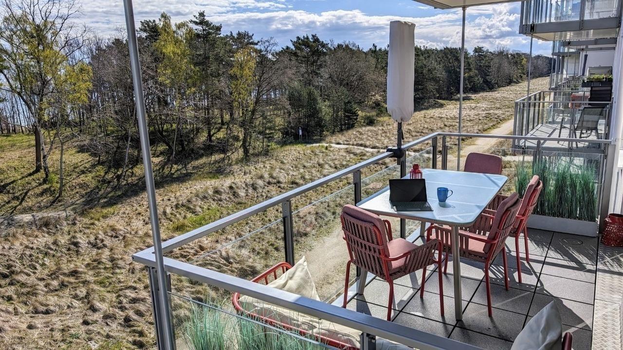 Terrasse mit Tisch, Stühlen und Blick auf Wald und Hügel