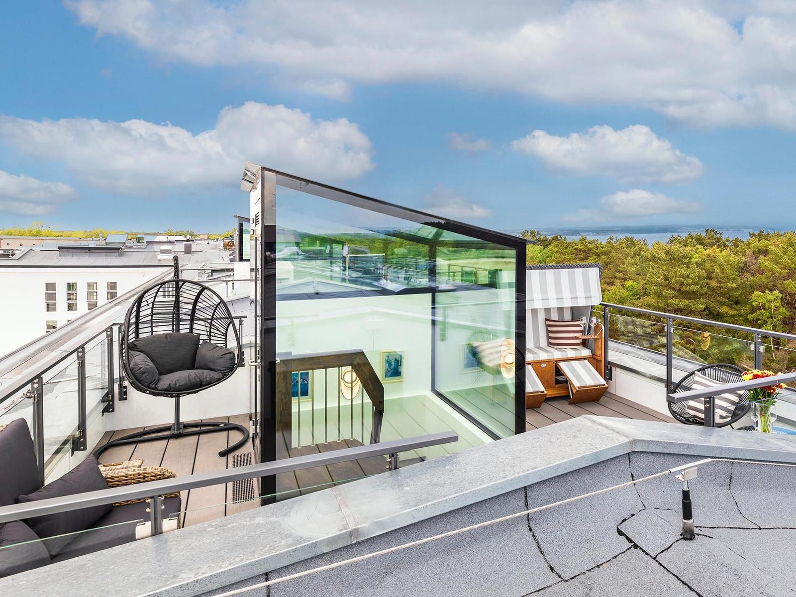 Dachterrasse mit Sitzgelegenheiten und Blick auf Wald und Wasser