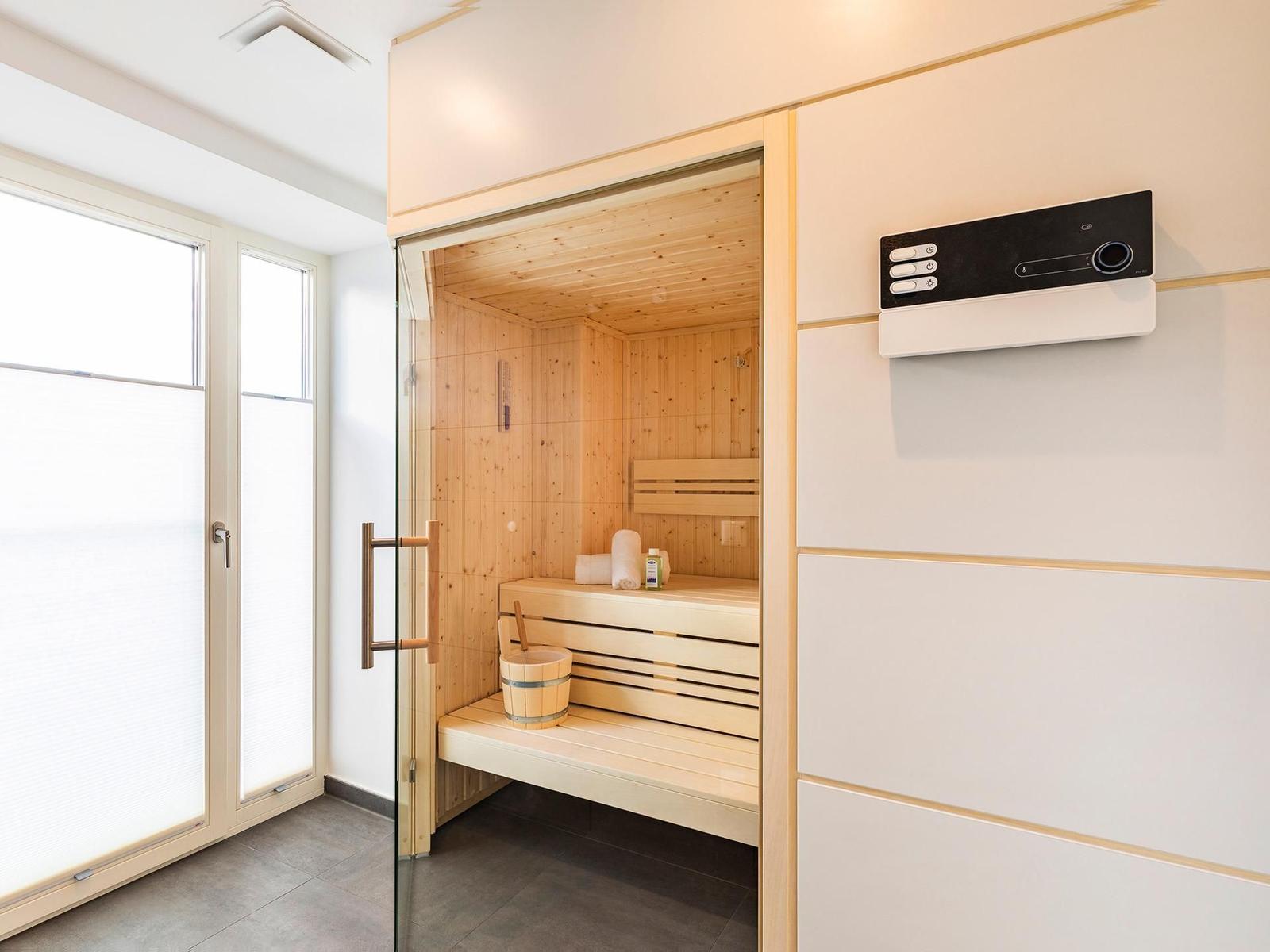 Sauna mit Holzbank, Eimer und Steuerung an der Wand