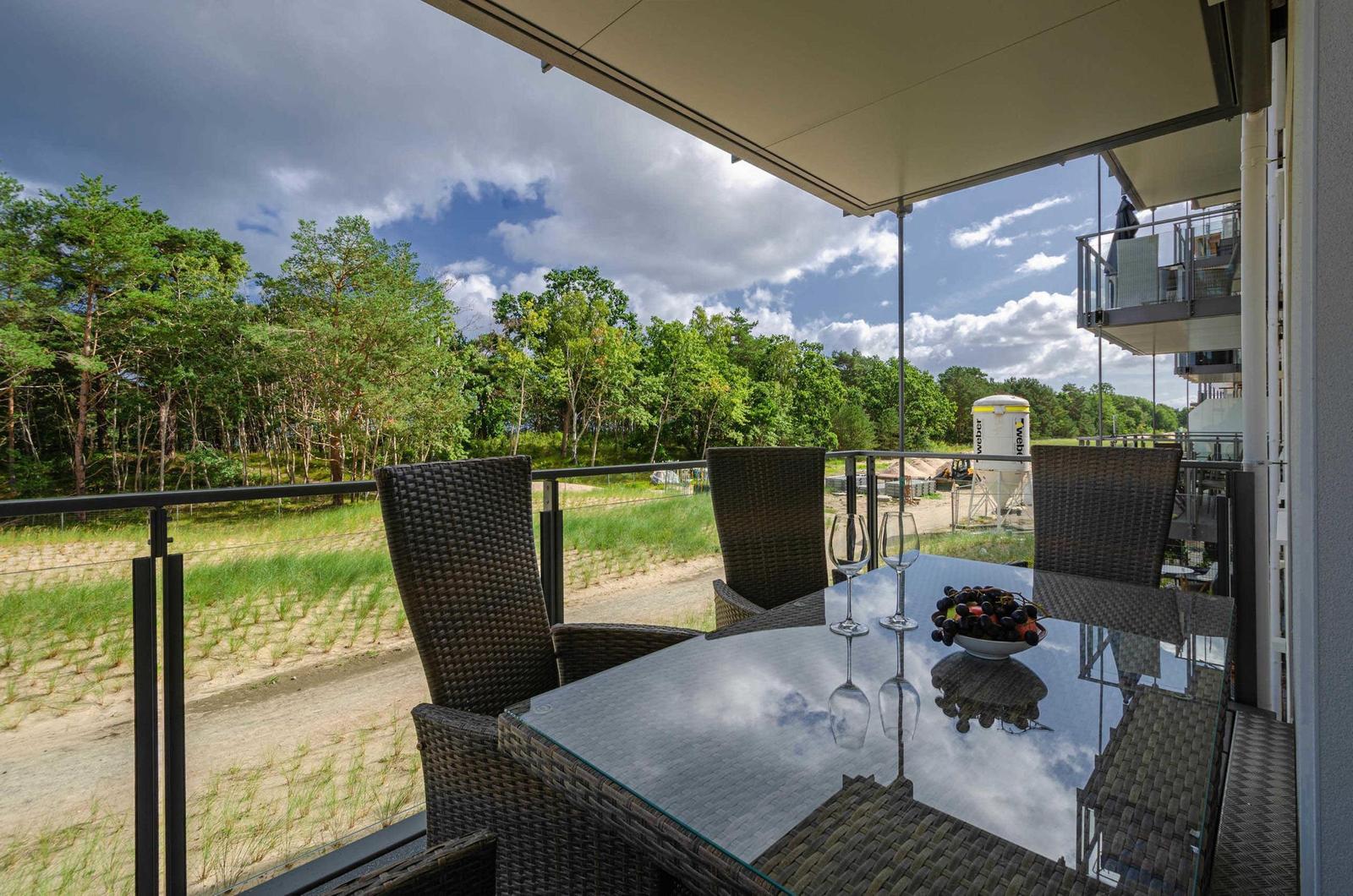 Terrasse mit Tisch und Stühlen, Blick auf Wald und Himmel.