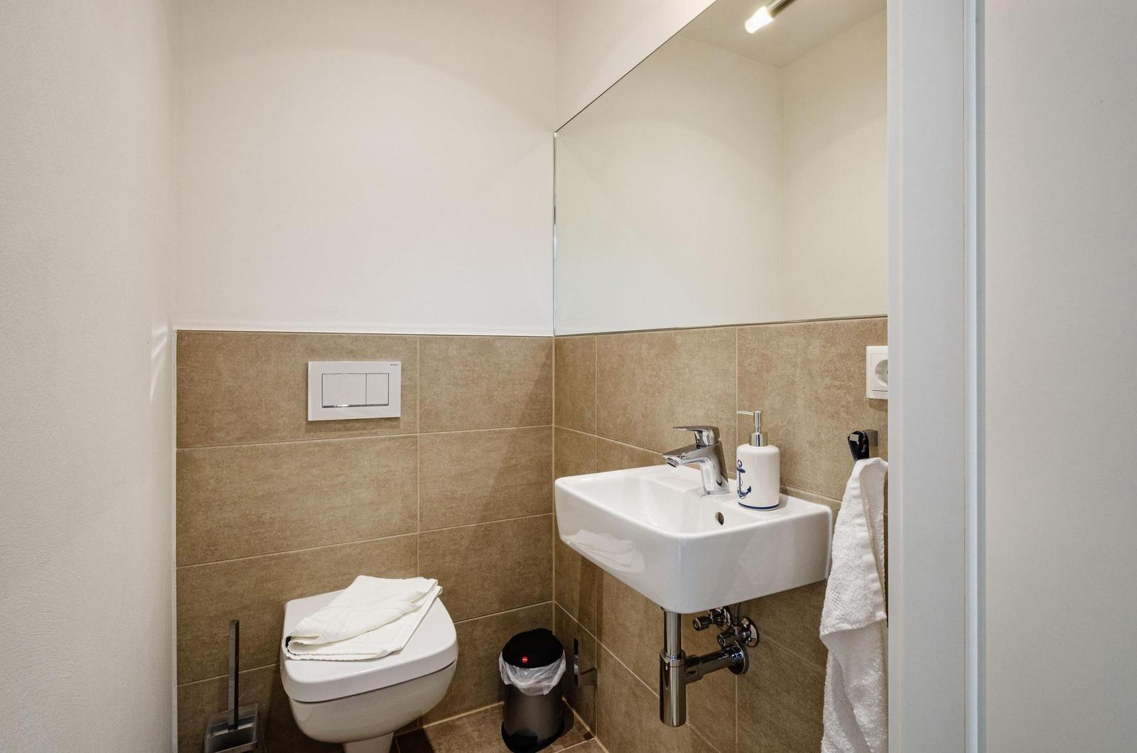 Badezimmer mit Waschbecken, Spiegel, Toilette und Handtuch.