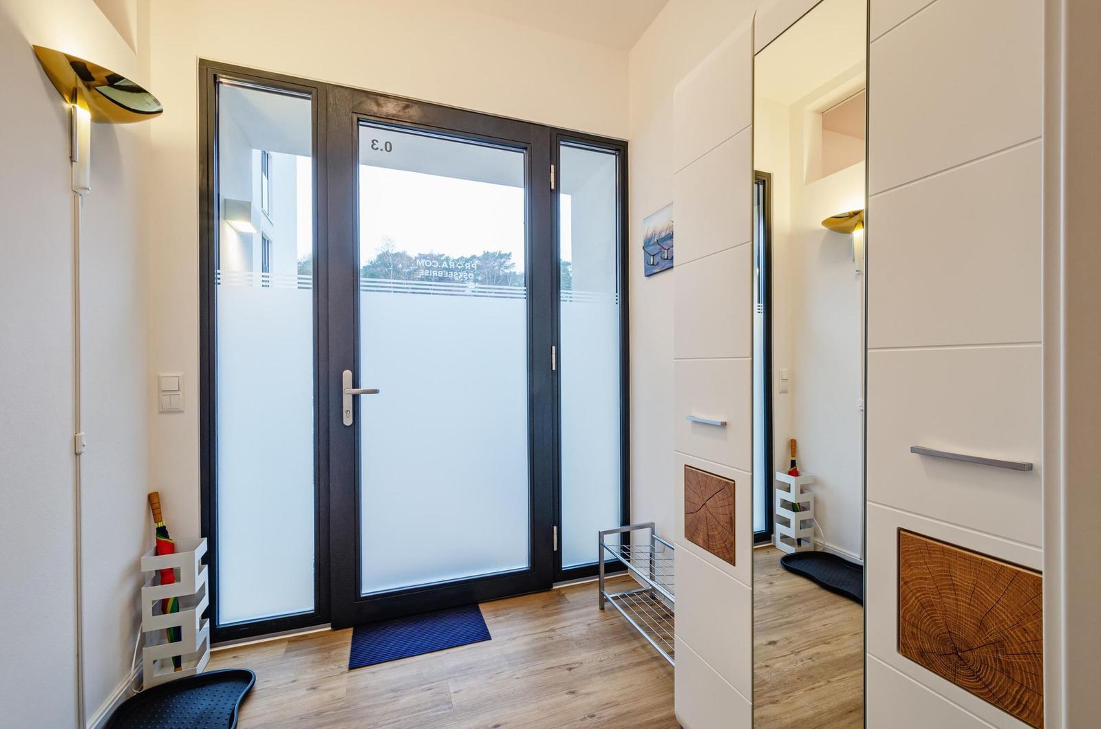 Eingangsbereich mit Glas-Tür und Holzboden. Spiegelwand und dekorative Holzplatten.