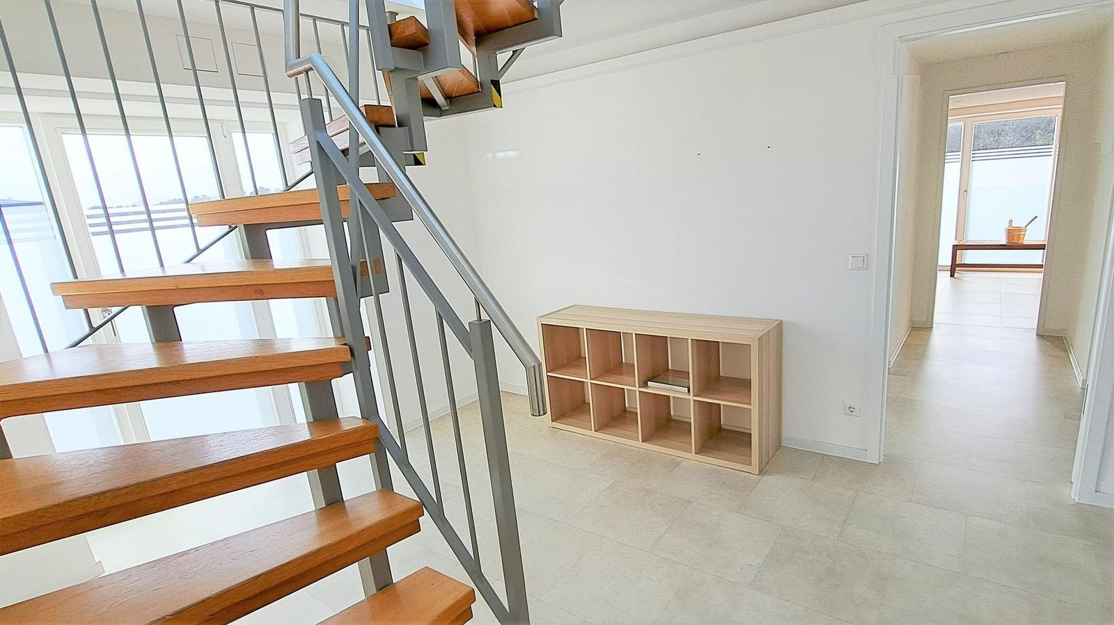 Haus mit Holztreppe, Bücherregal und Blick auf Terrasse.