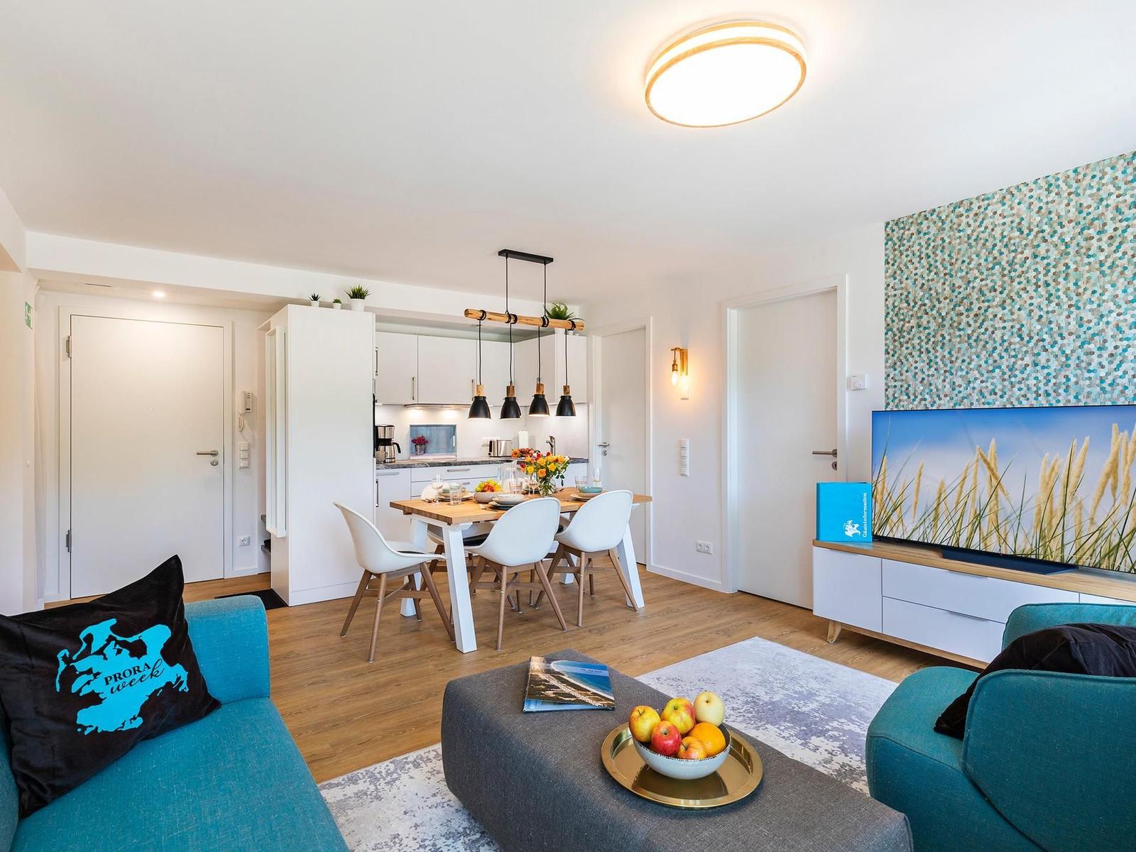 Wohn-/Essbereich: Sitzgruppe mit Couch und Sessel, Smart-TV, Zugang zum Balkon, Esstisch mit 5 Stühlen