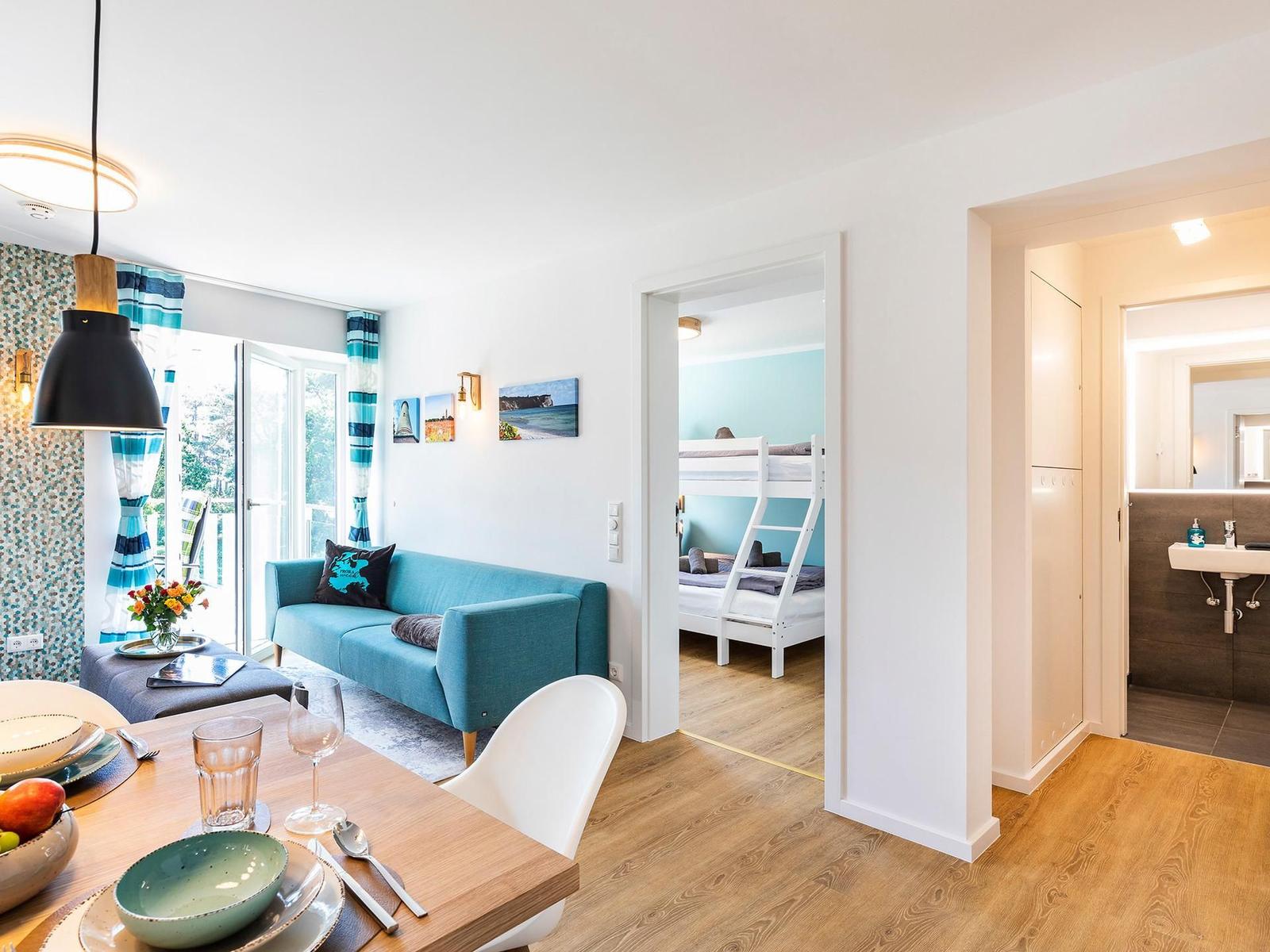 Wohn-/Essbereich: Sitzgruppe mit Couch und Sessel, Smart-TV, Zugang zum Balkon, Esstisch mit 5 Stühlen