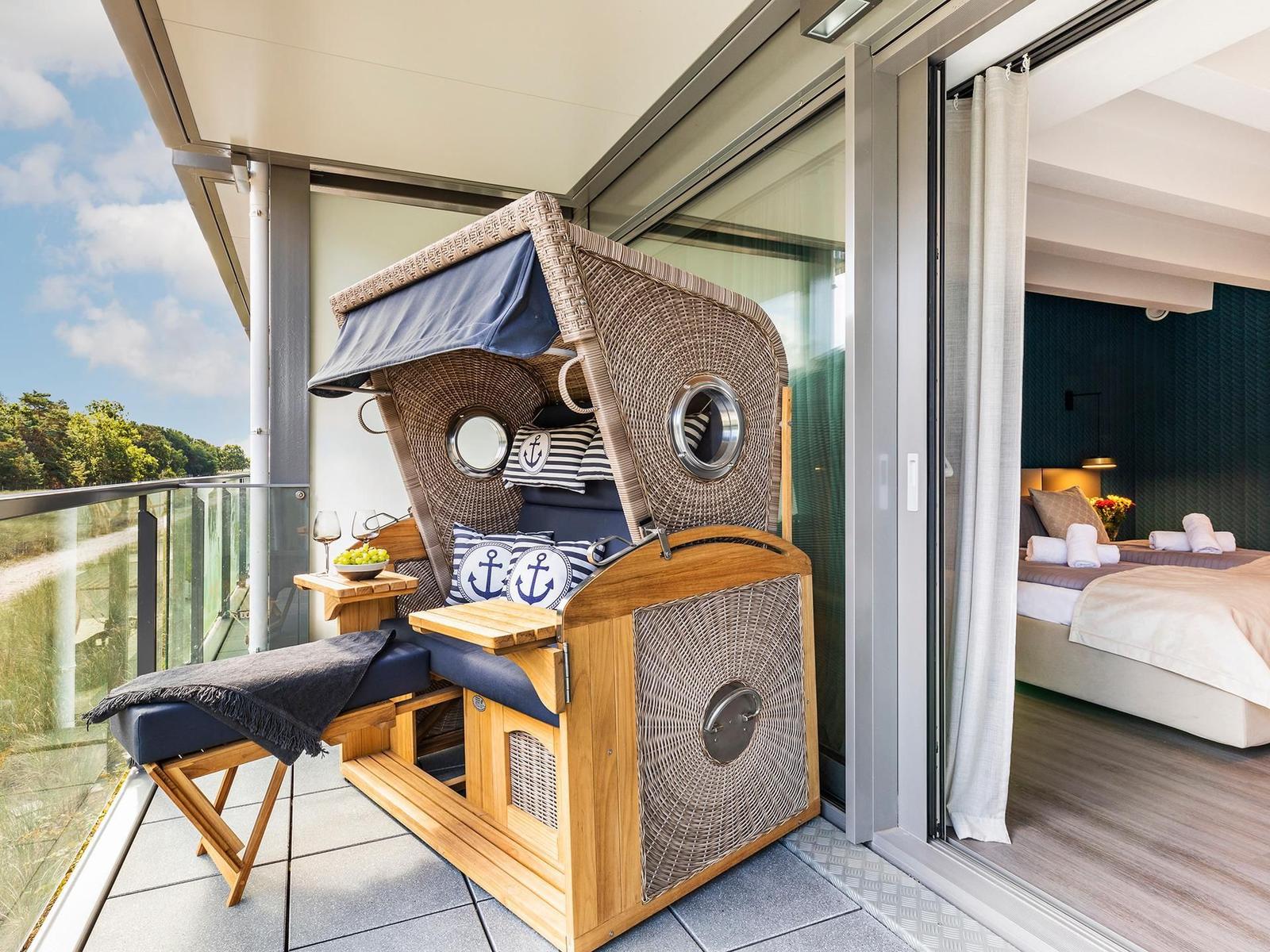 Terrasse mit Bootsbalkonmöbeln und Blick auf Wald. Schlafzimmer mit Bett und dunkler Wand.