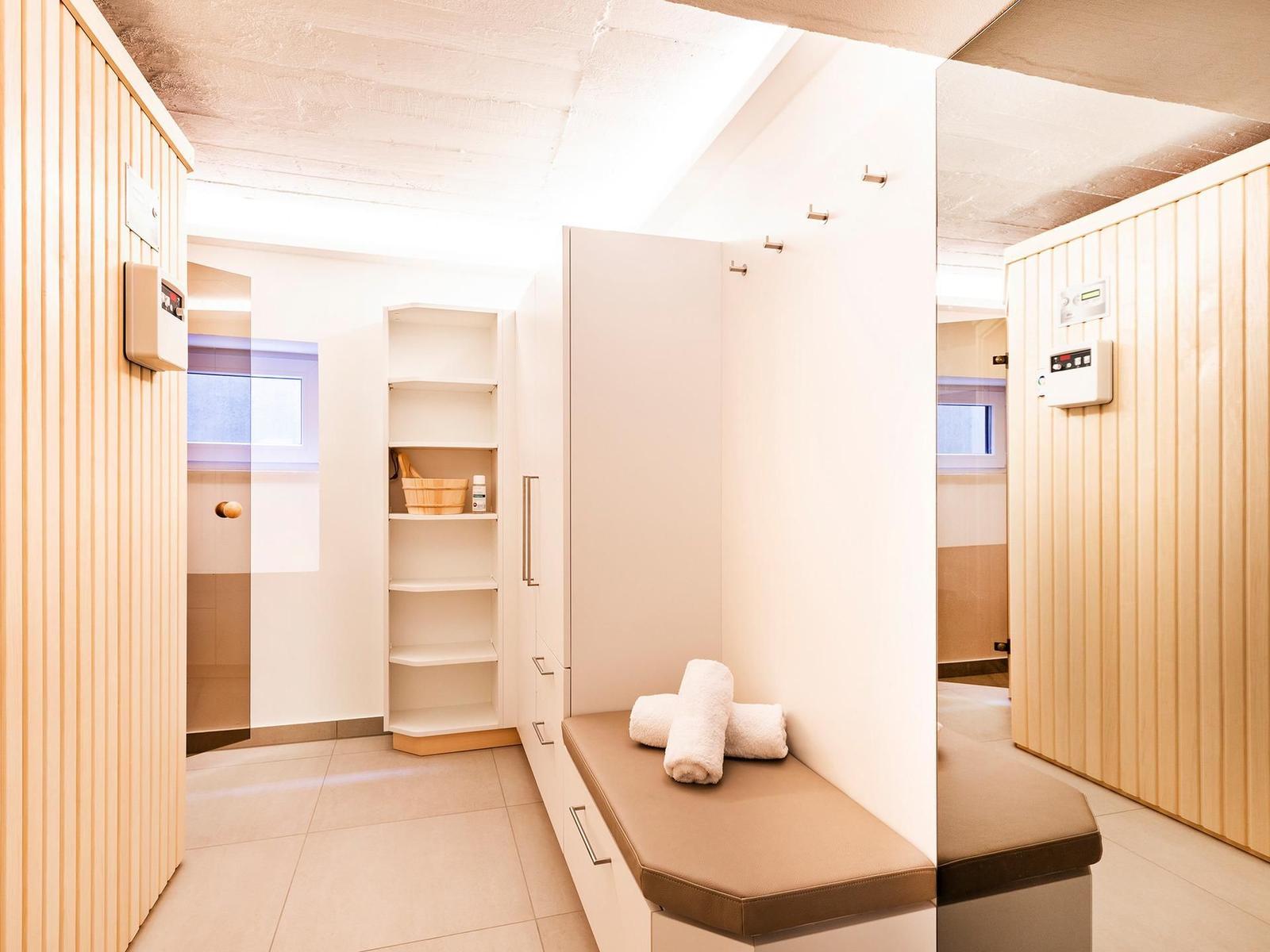 Sauna mit Holzwand, Sitzbank und Regal mit Badartikeln.