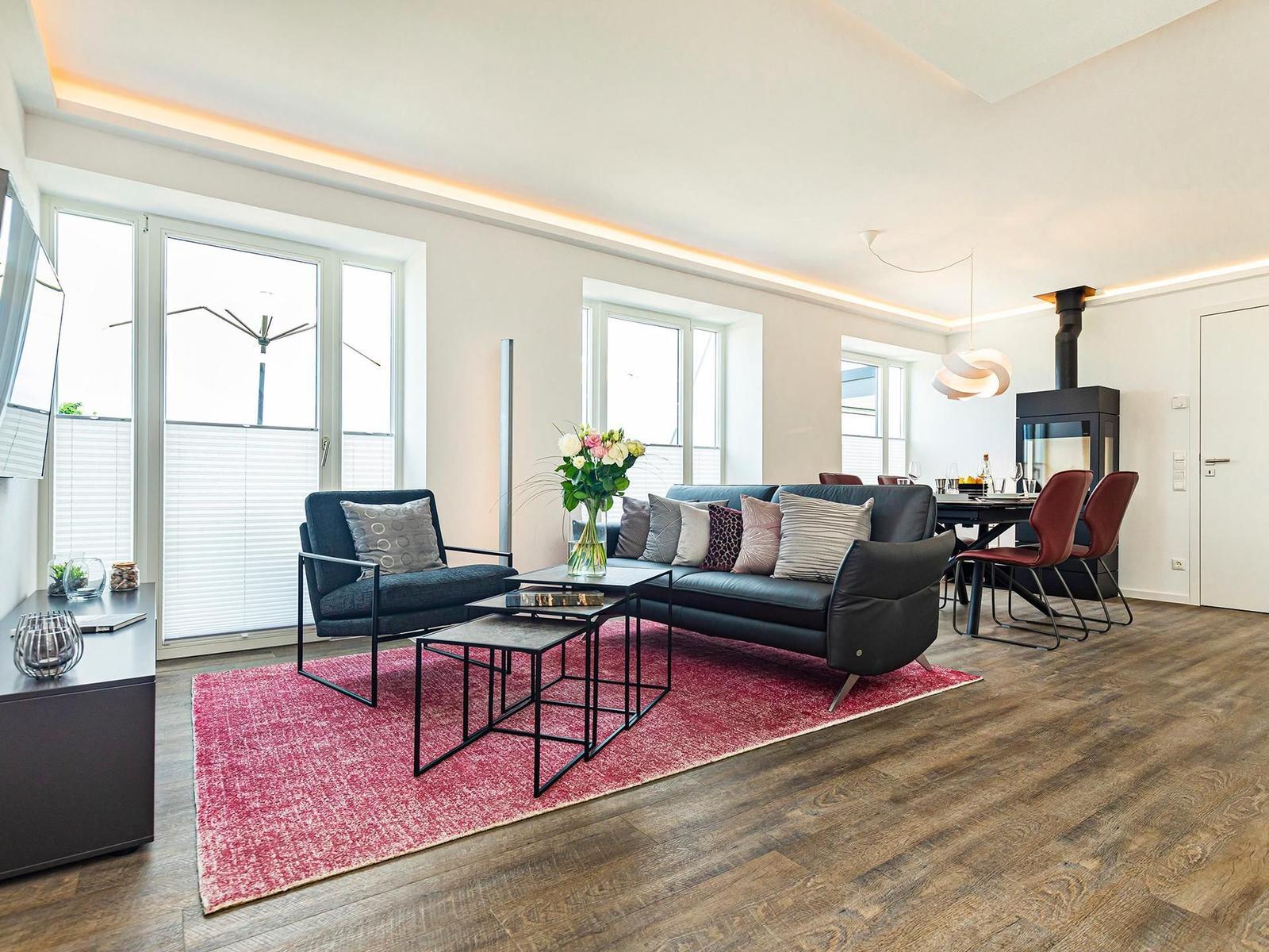 Wohnbereich/Essbereich: Sofa, TV, Beschattungs-Plissess, Treppenaufgang zur Dachterrasse, Zugang zum Balkon