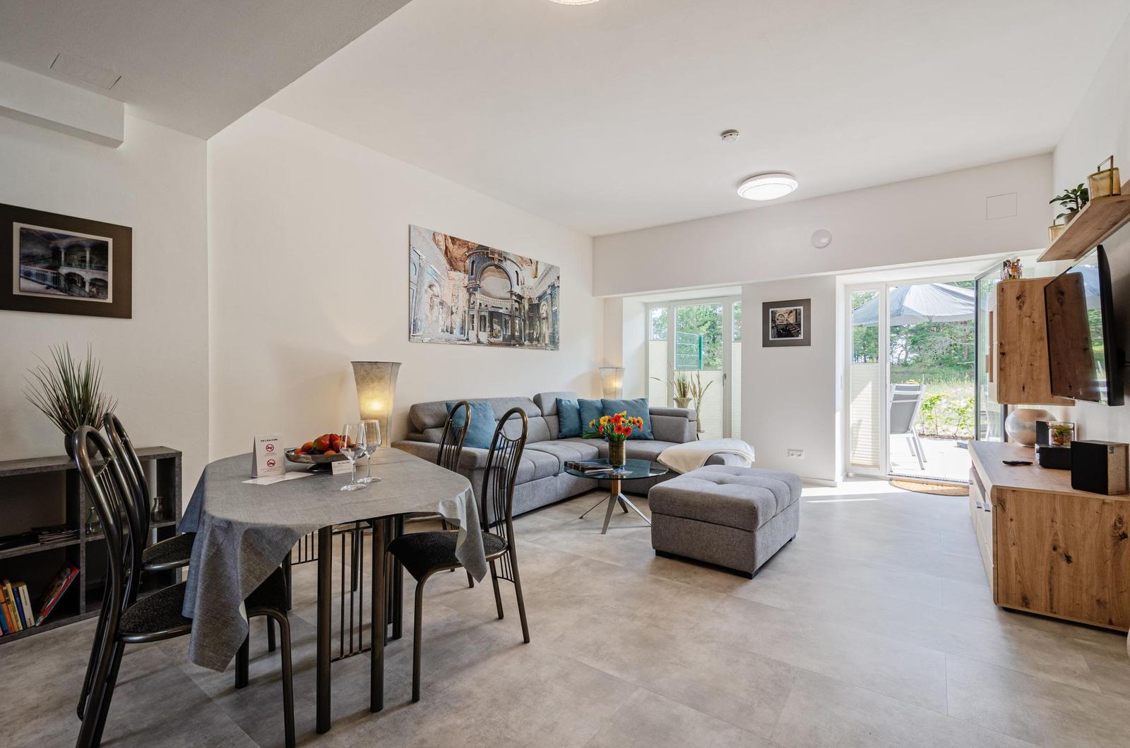 Wohnzimmer: Schlafsofa und Sessel, TV, Essbereich, Zugang zur Terrasse