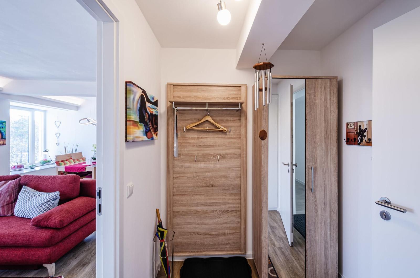 Entryway with closet and view into living room with red sofa.