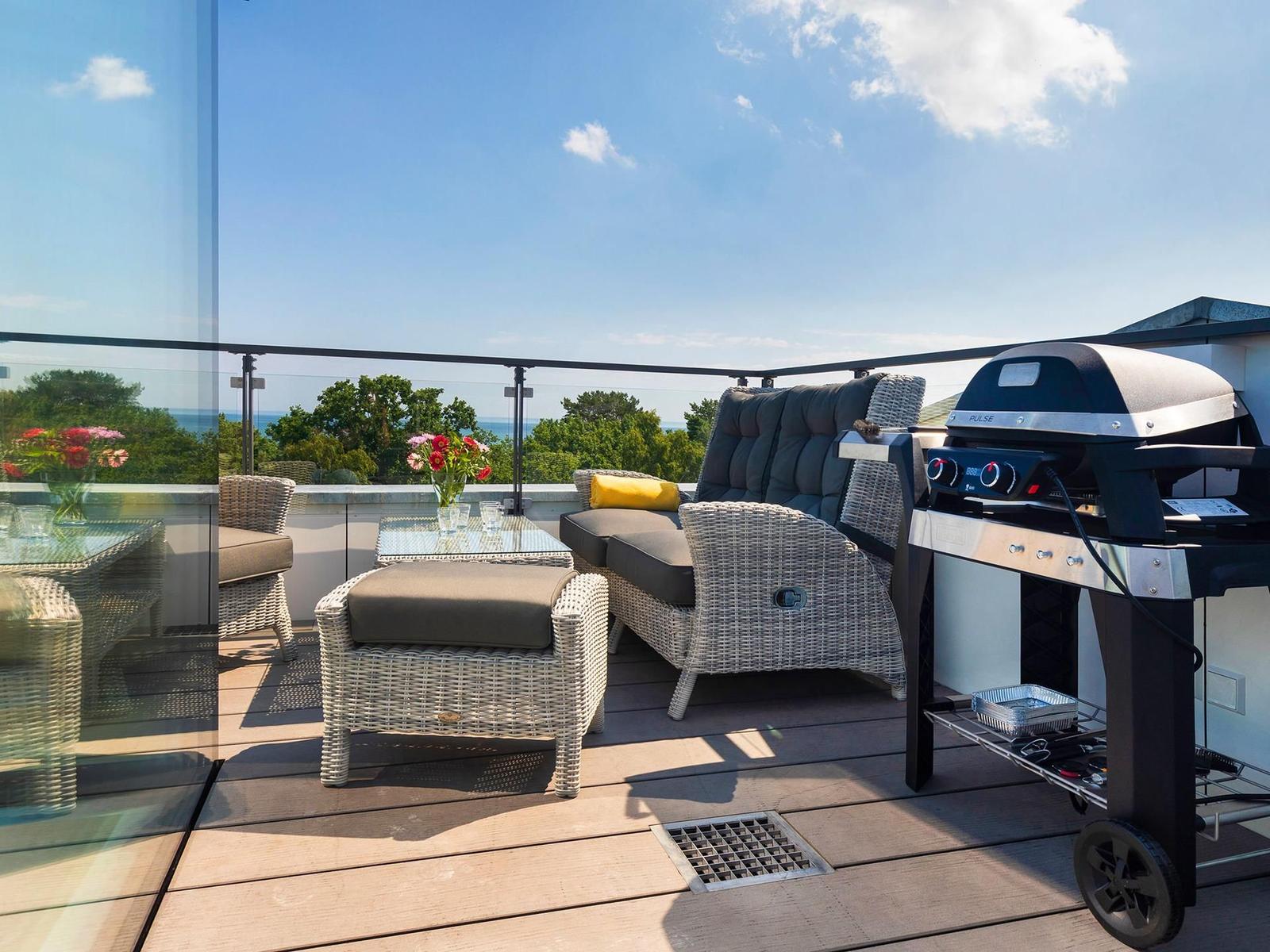 Terrasse mit Sitzgruppe, Grill und Meerblick.