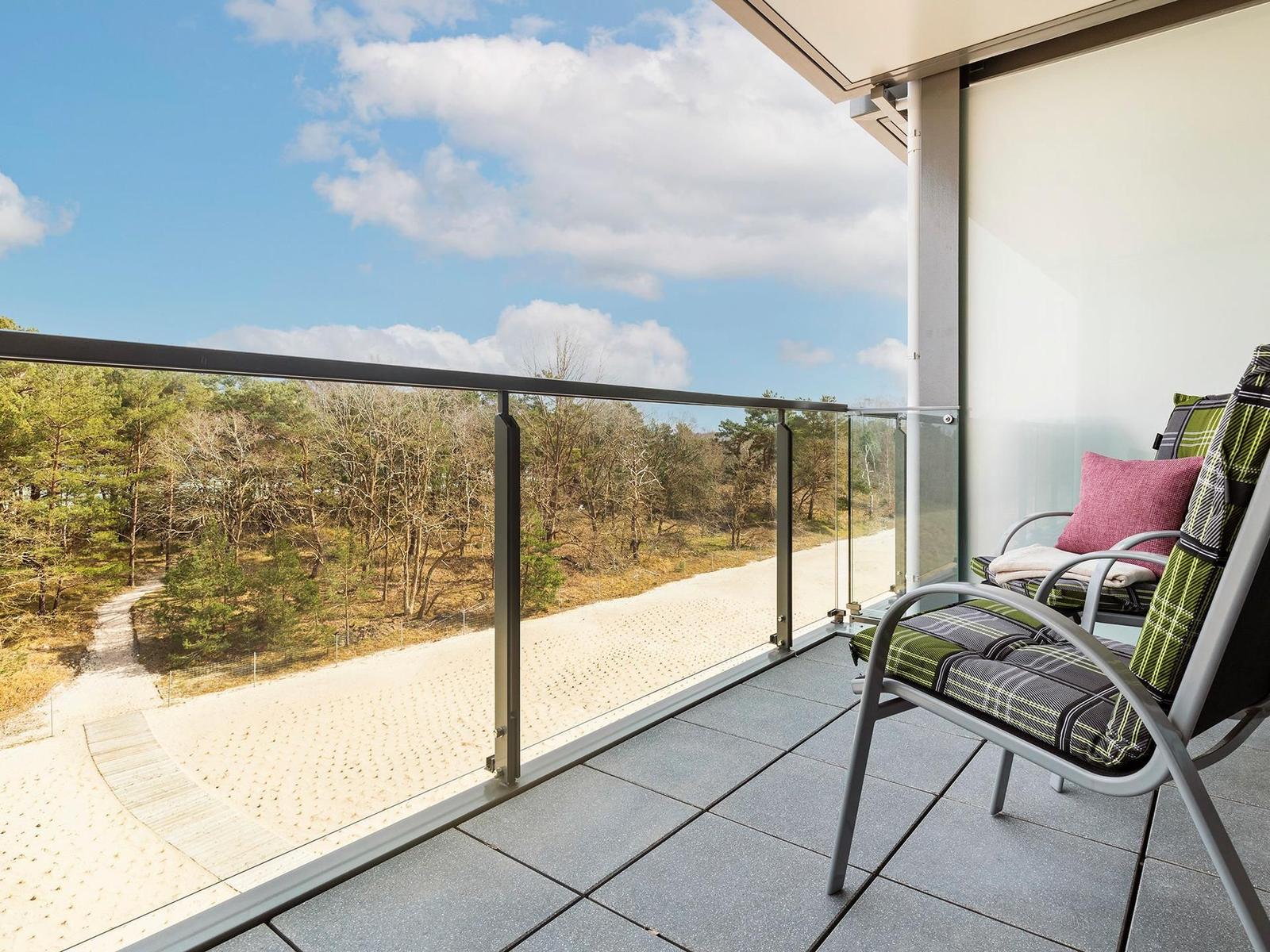 Terrasse mit Sitzgelegenheit und Blick auf Wald und Himmel.