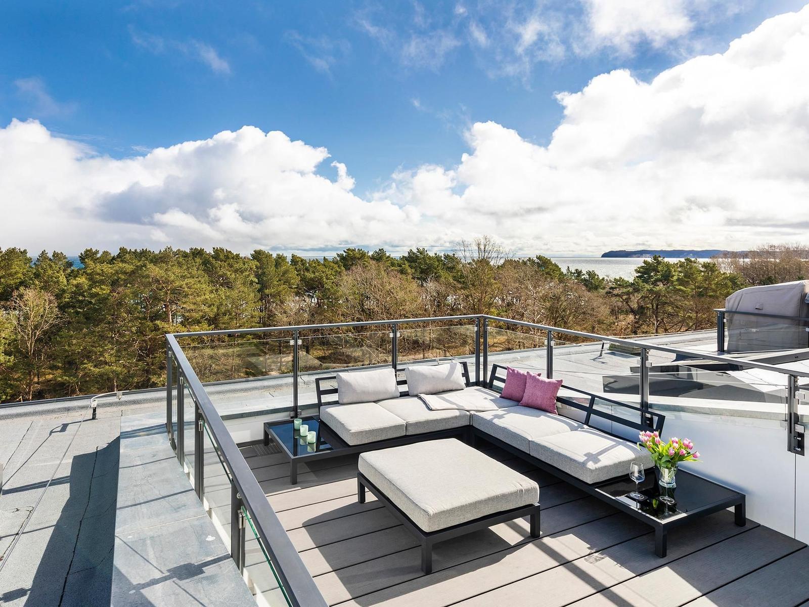 Terrasse mit Sitzgruppe, Blick auf Wald und Meer.