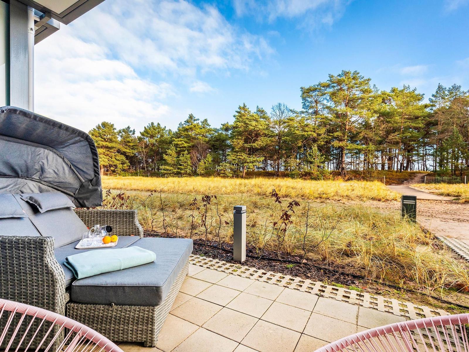 Terrasse mit Liegestuhl, Blick auf Wald und Grasland.