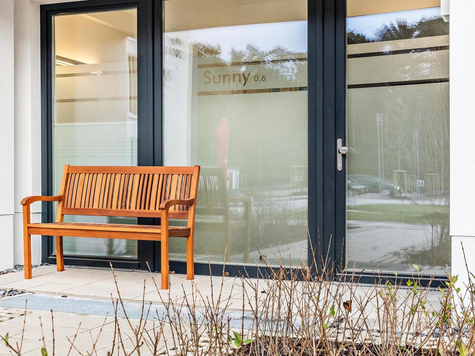 Holzbank vor Glasfront mit Aufschrift Sunny 0.6
