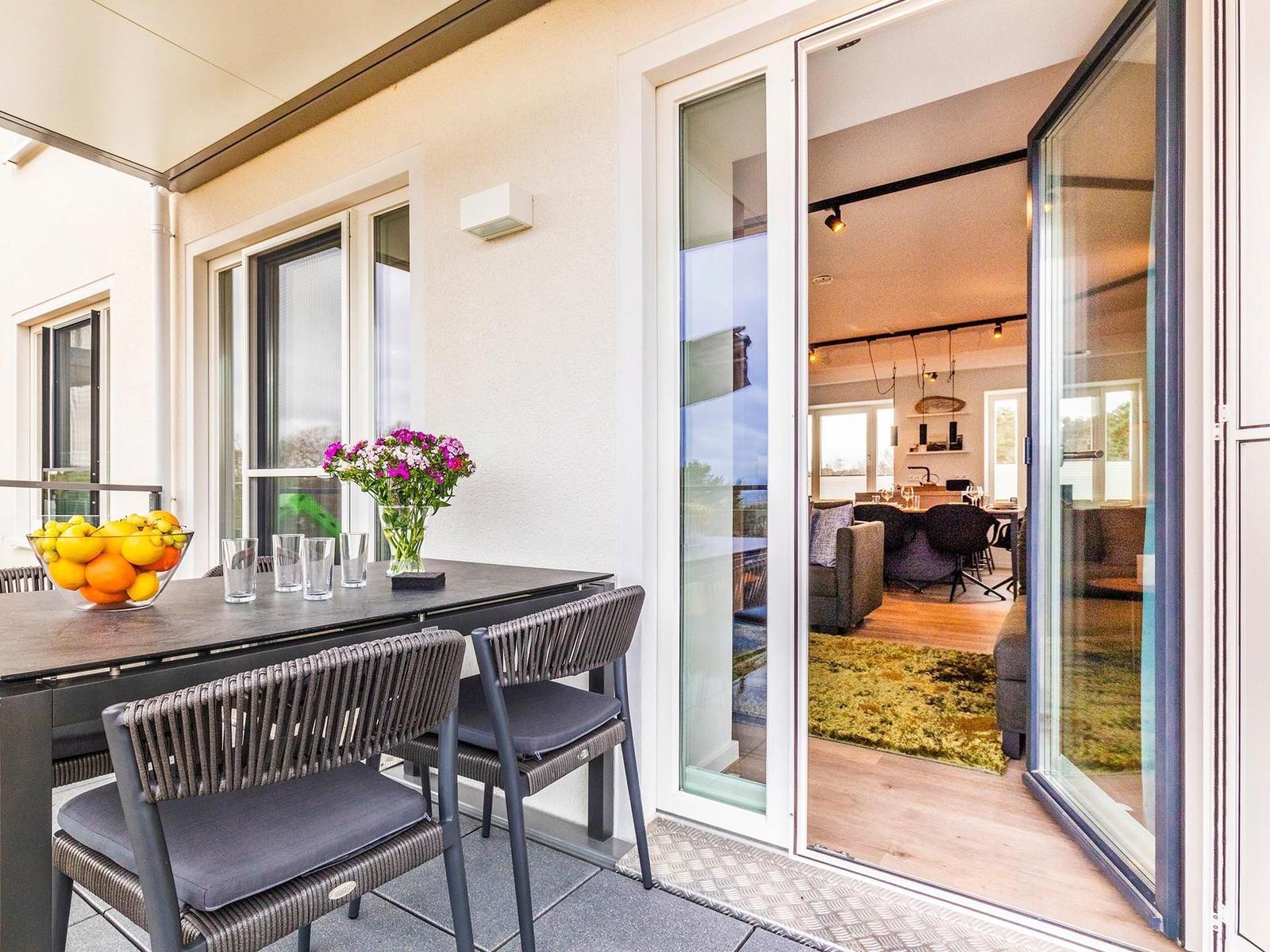 Wohn-/Essbereich: Couchgruppe mit Tisch, Smart-TV, Essbereich, Zugang zum Balkon mit Tisch und Stühlen (Seeseite), Sonne