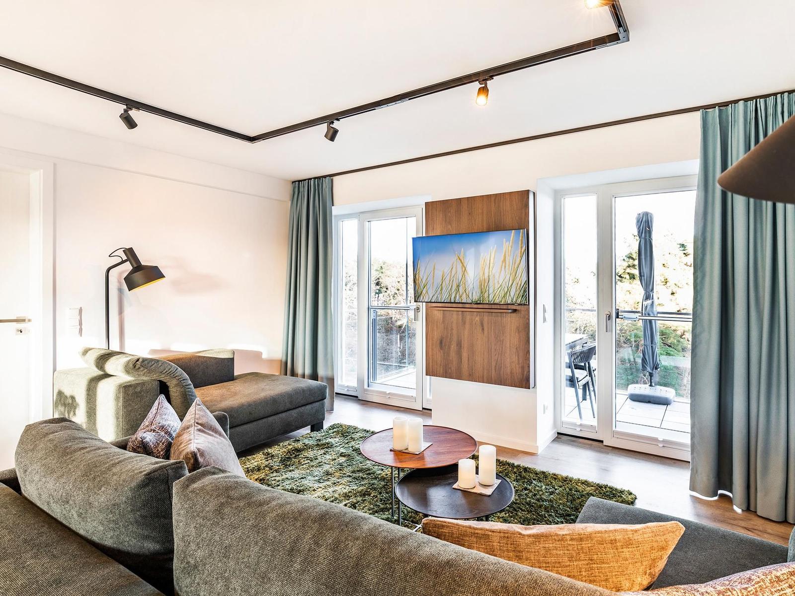 Wohn-/Essbereich: Couchgruppe mit Tisch, Smart-TV, Essbereich, Zugang zum Balkon mit Tisch und Stühlen (Seeseite), Sonne