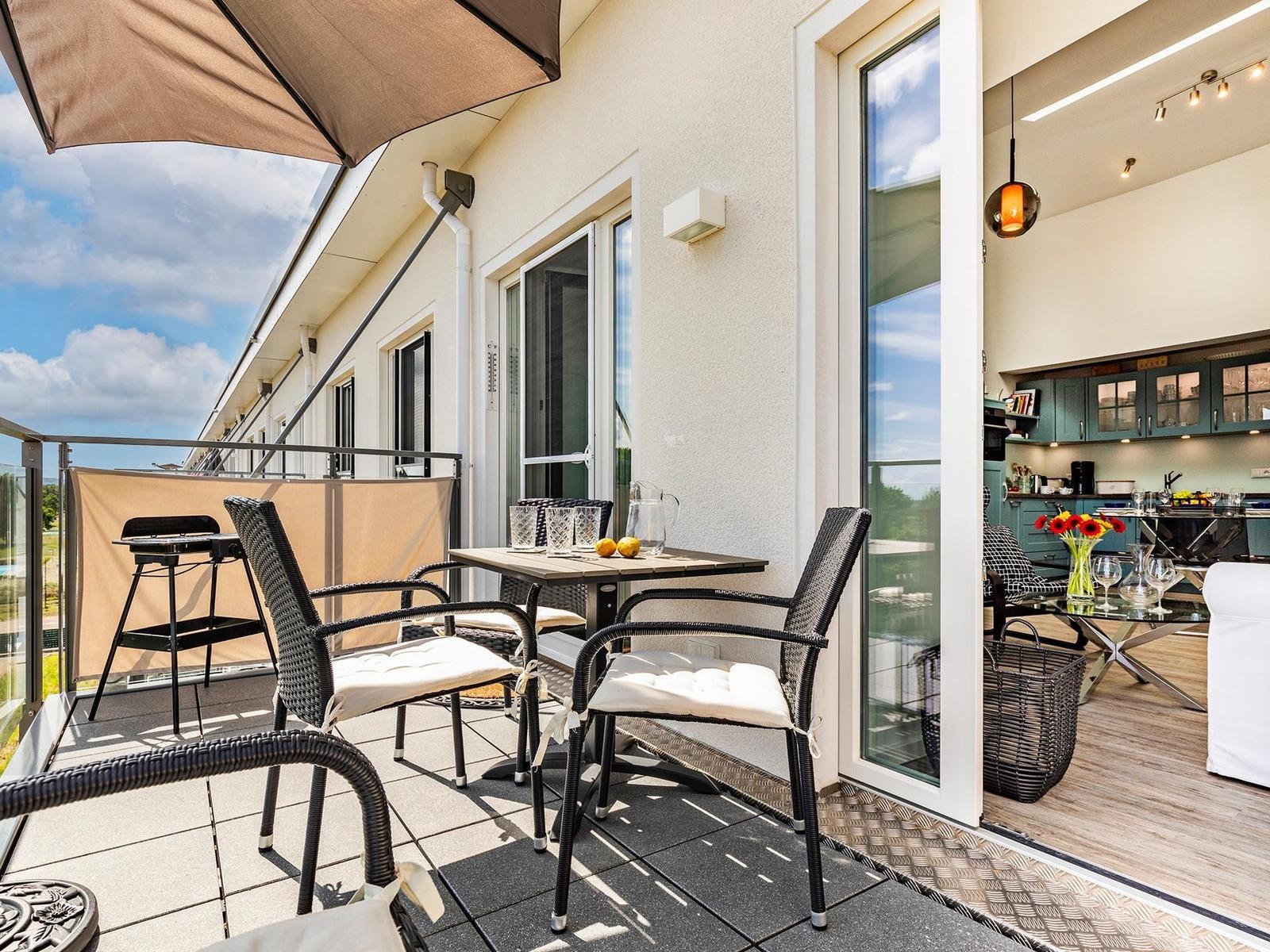 Terrace with table, chairs, and awning. Entrance into living area with kitchen.