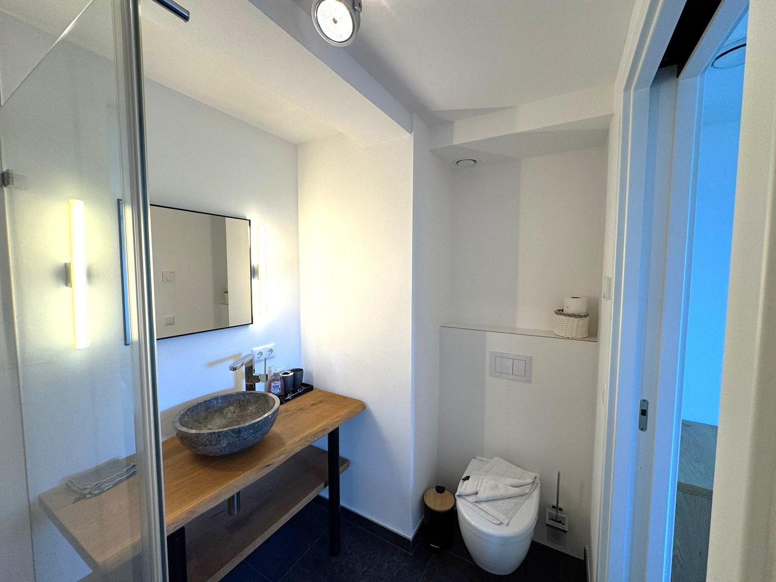 Badezimmer mit Waschtisch, Spiegel und Toilette.