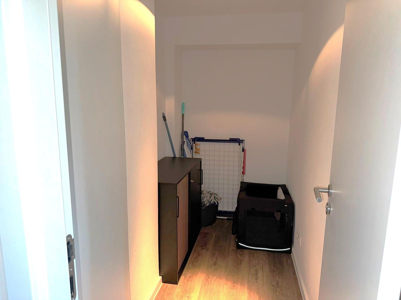 Flur mit Schrank, Staubsauger und Hundekäfig.