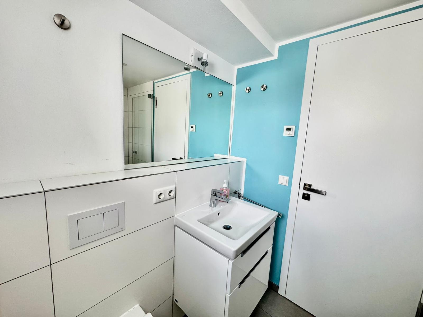 Badezimmer mit Waschbecken, Spiegel und blauer Wand